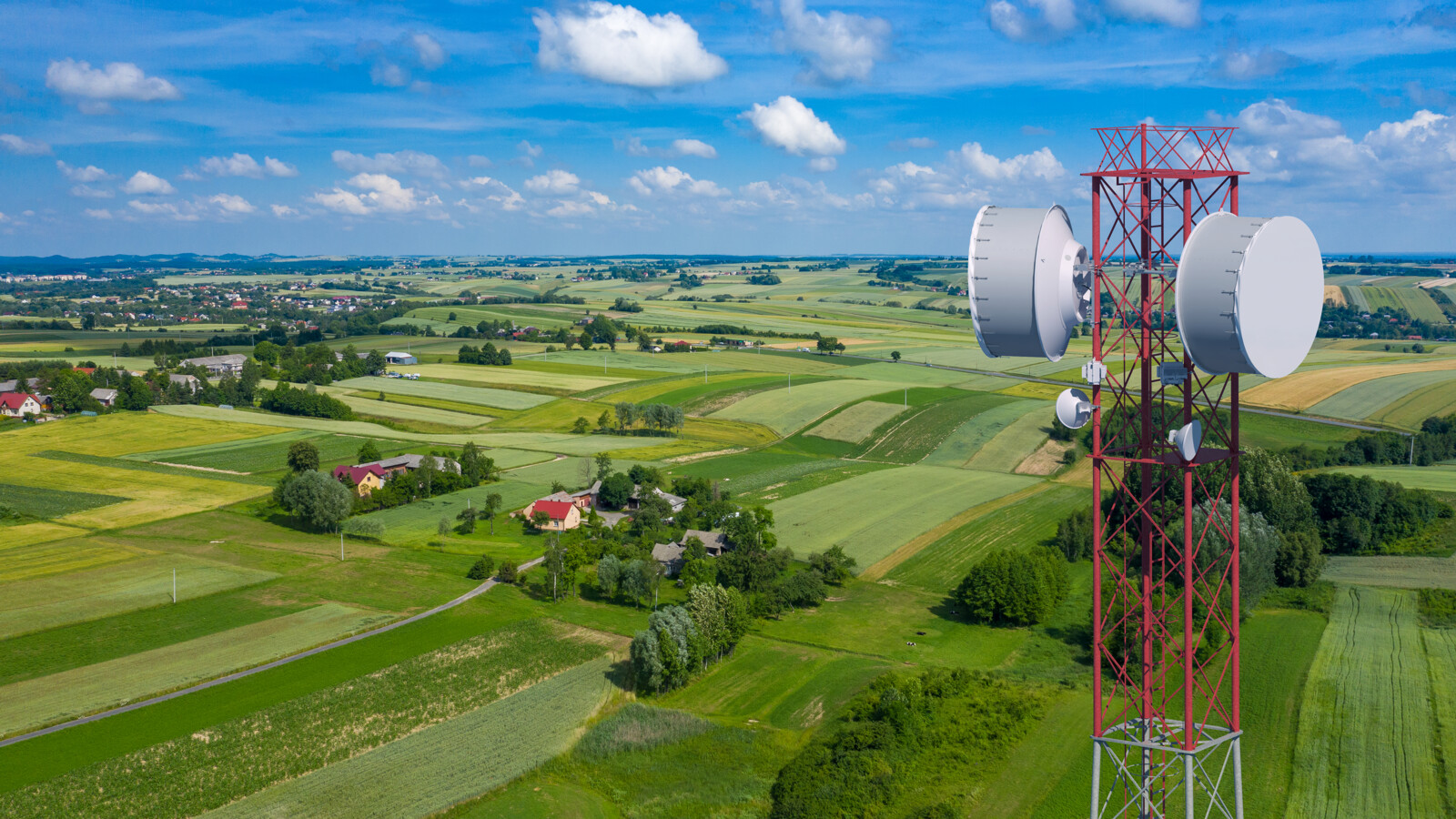 Microwave telecom tower overlooking rural fields, illustrating transmit power considerations in long-distance links.