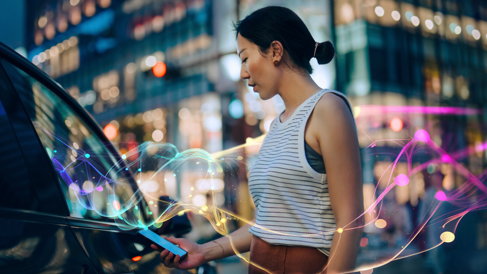 Person with mobile phone in hand beside a car.