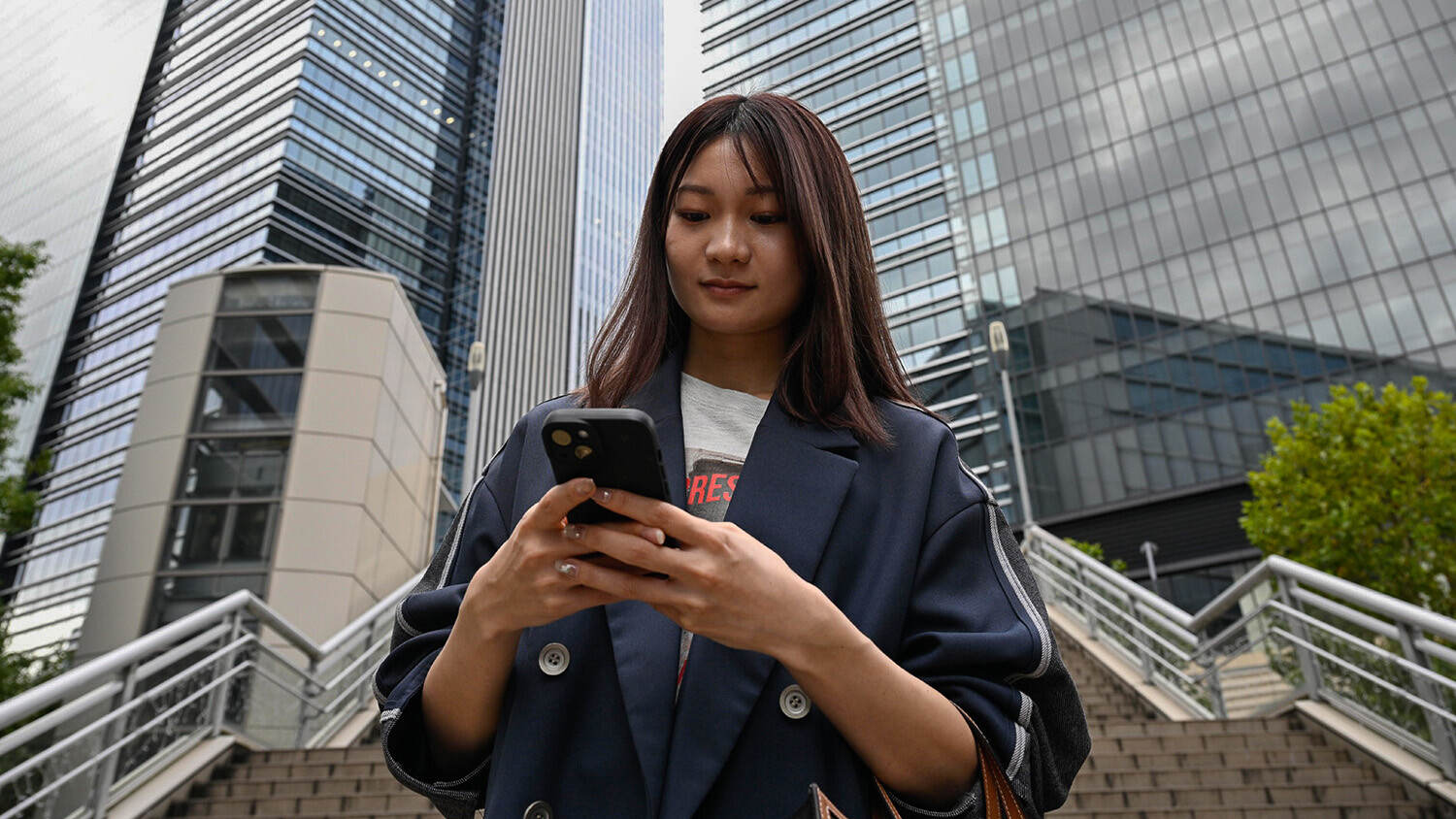 Woman texting on phone in business district.
