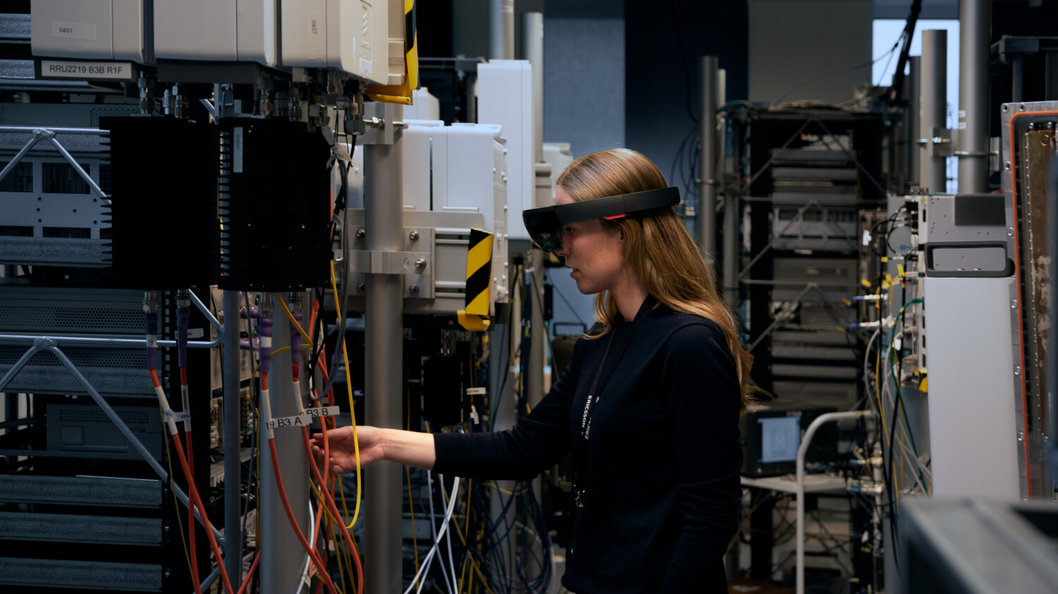 Engineer inspecting cables in a server room with AR glasses on.