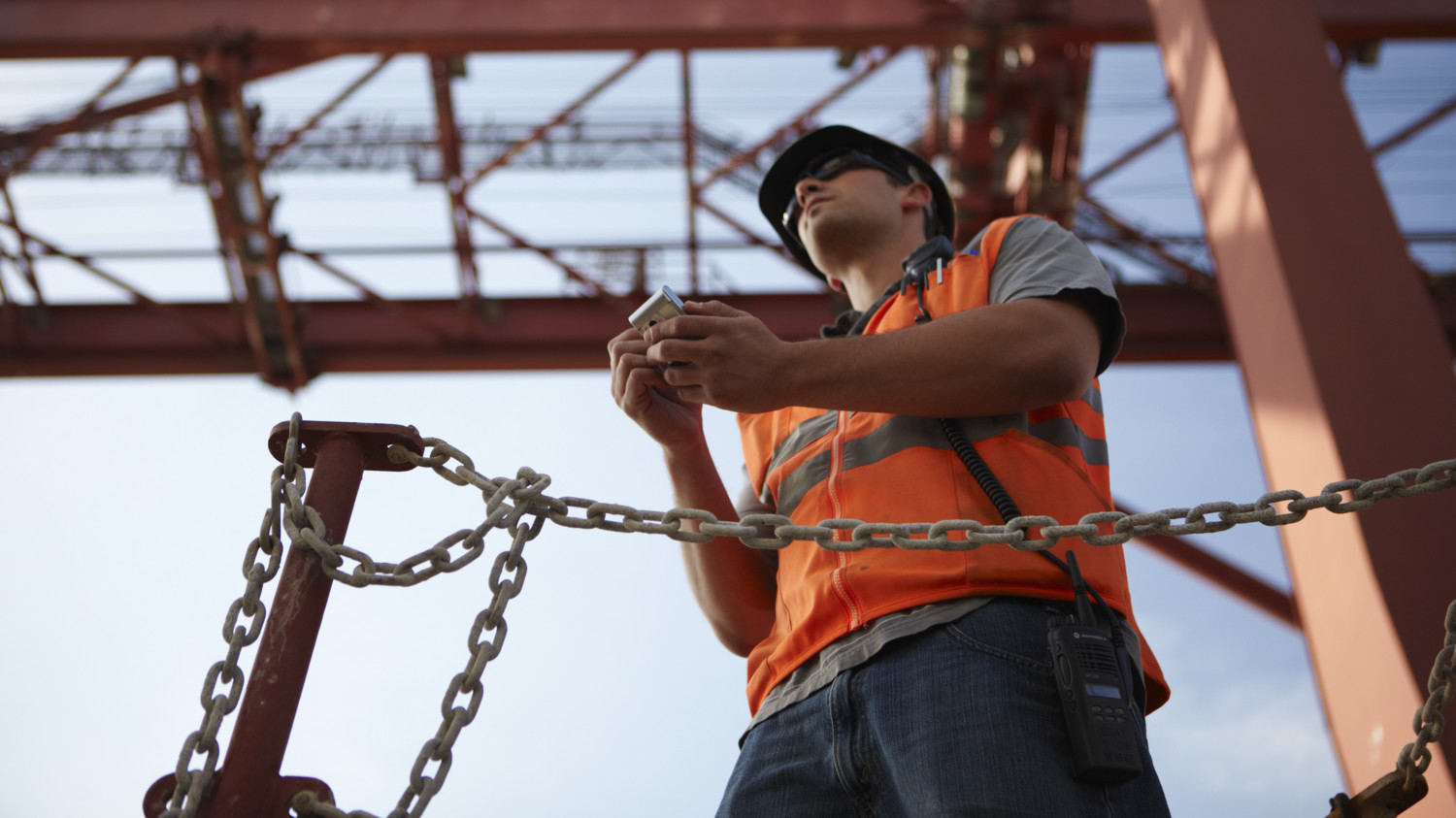 Man working on a construction site, holding a mobile phone.