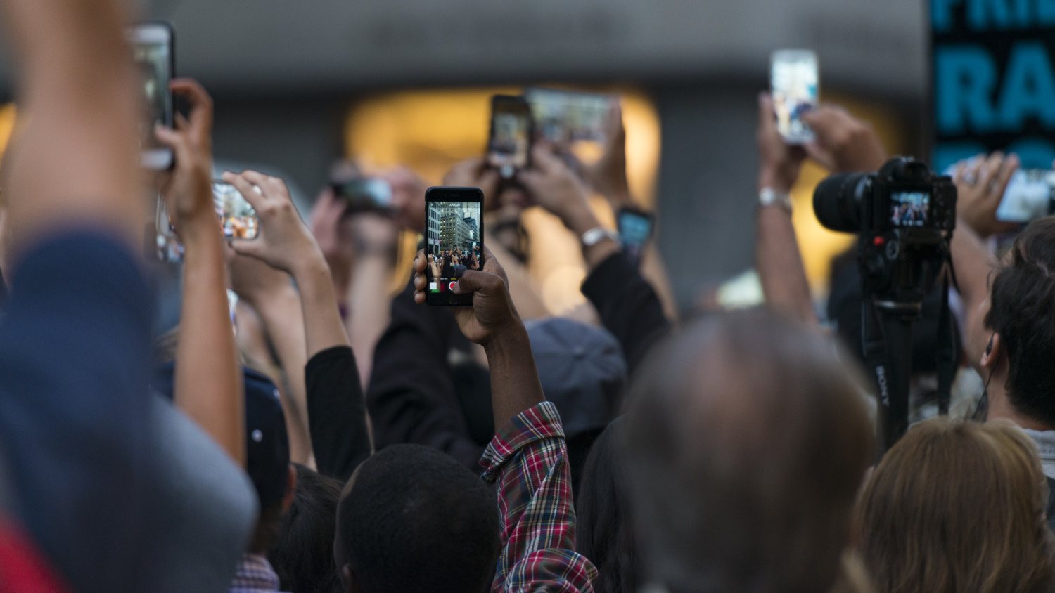 Crowd holding up devices to take pictures
