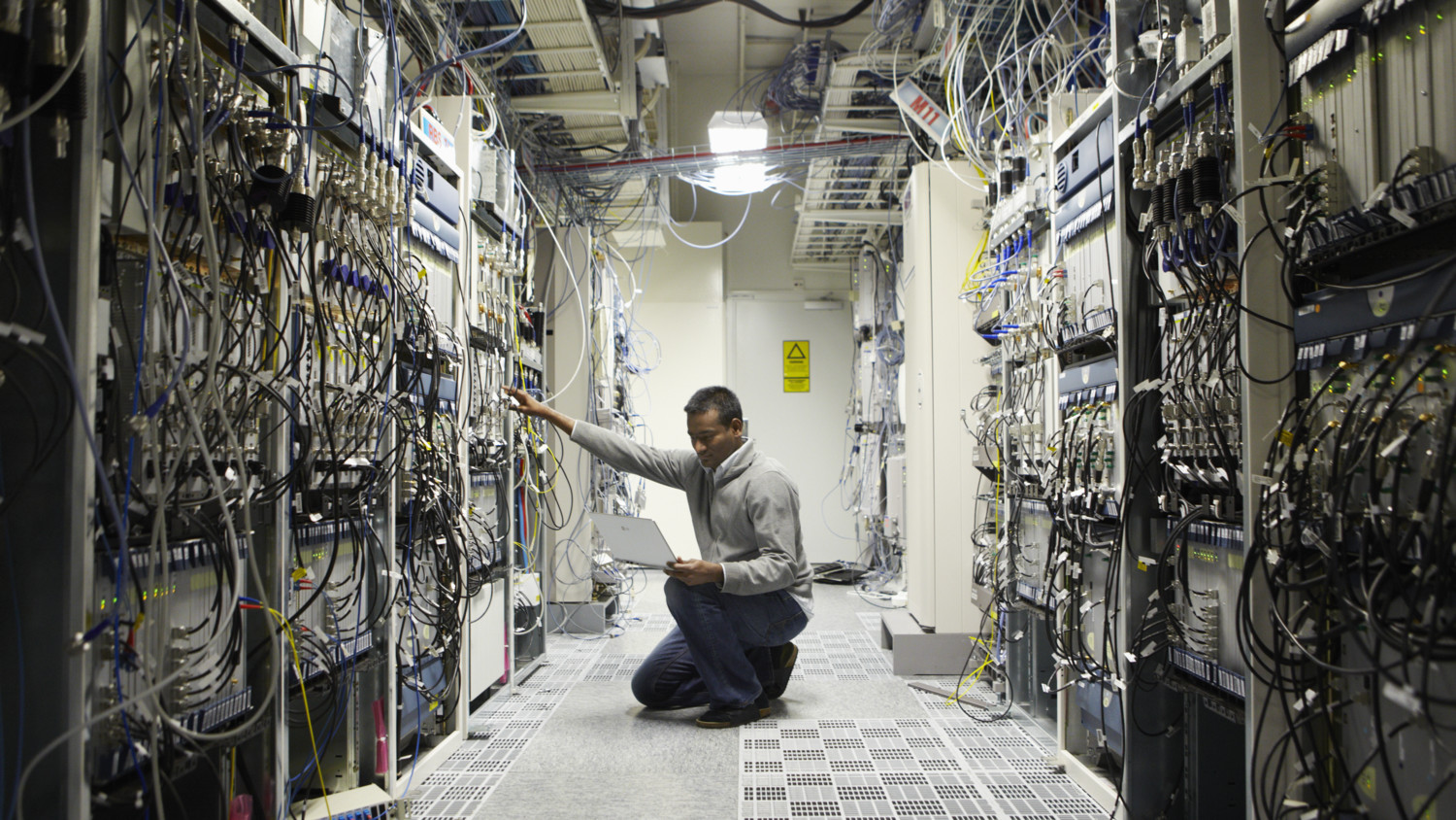 A technician sitting on his knees in a lab and monitoring