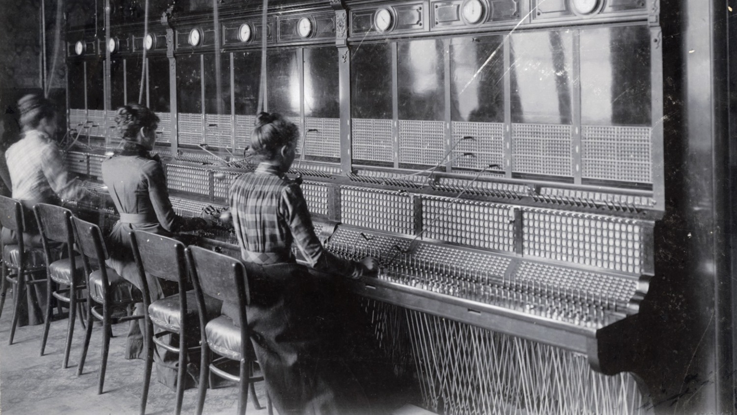 Three telephone operators from the early 1900s sitting at a switch board 