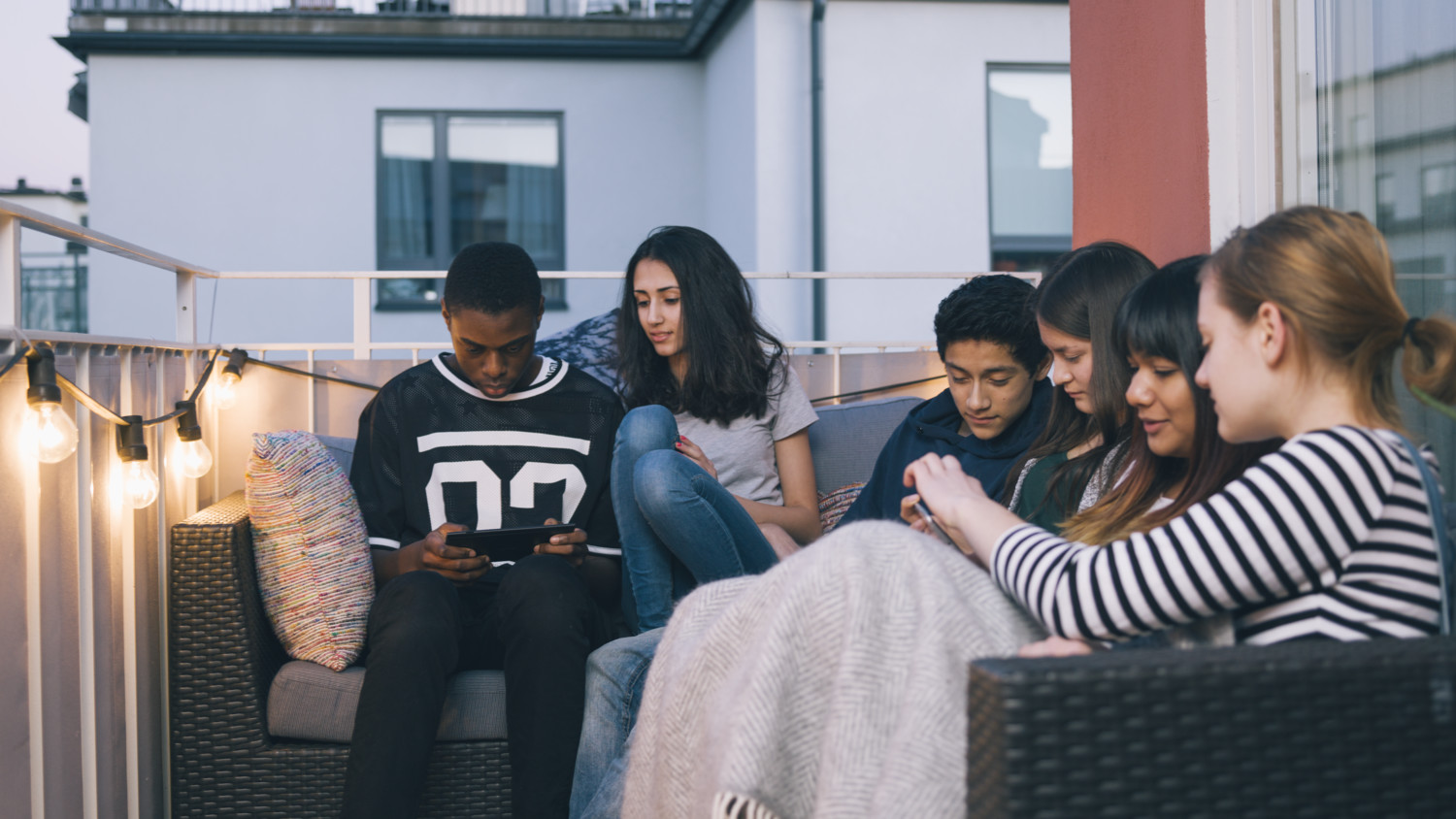 Um grupo de adolescentes que olham a mídia em uma varanda.