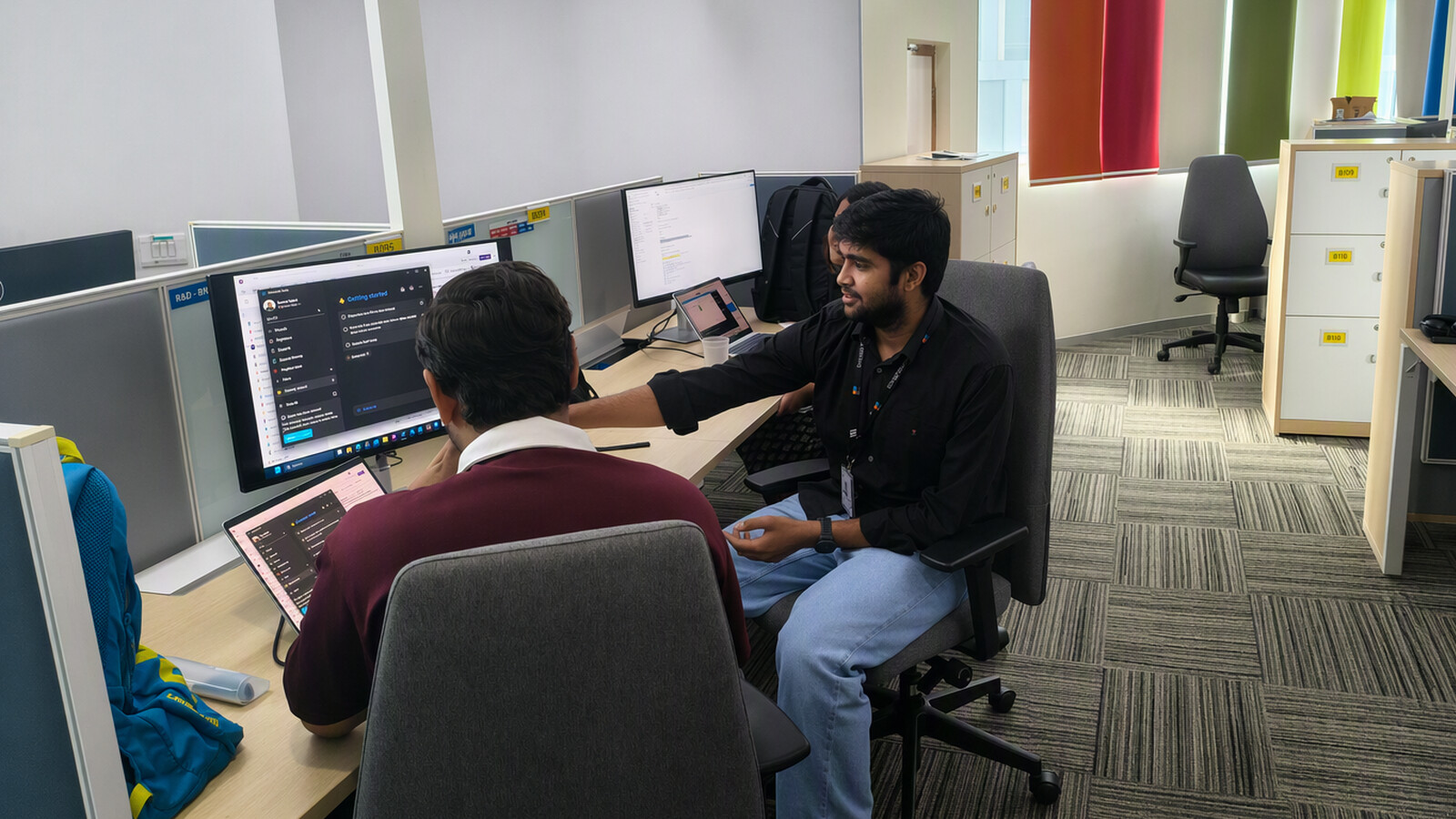 Purval and his colleague working at a desk.