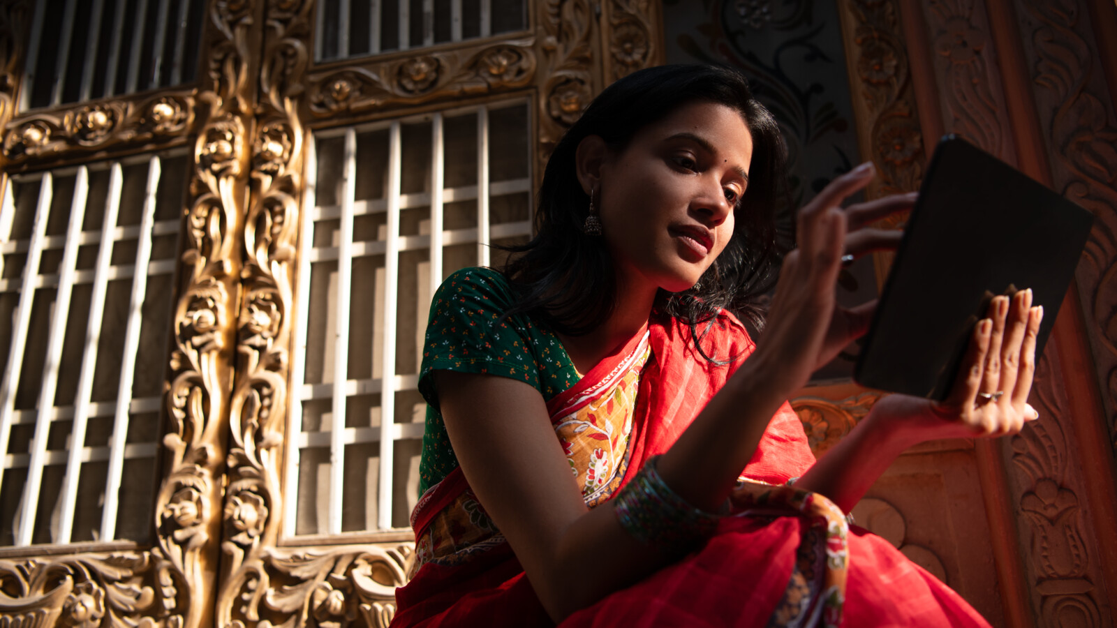 A young woman using a tablet, featuring sunlight and detailed architecture