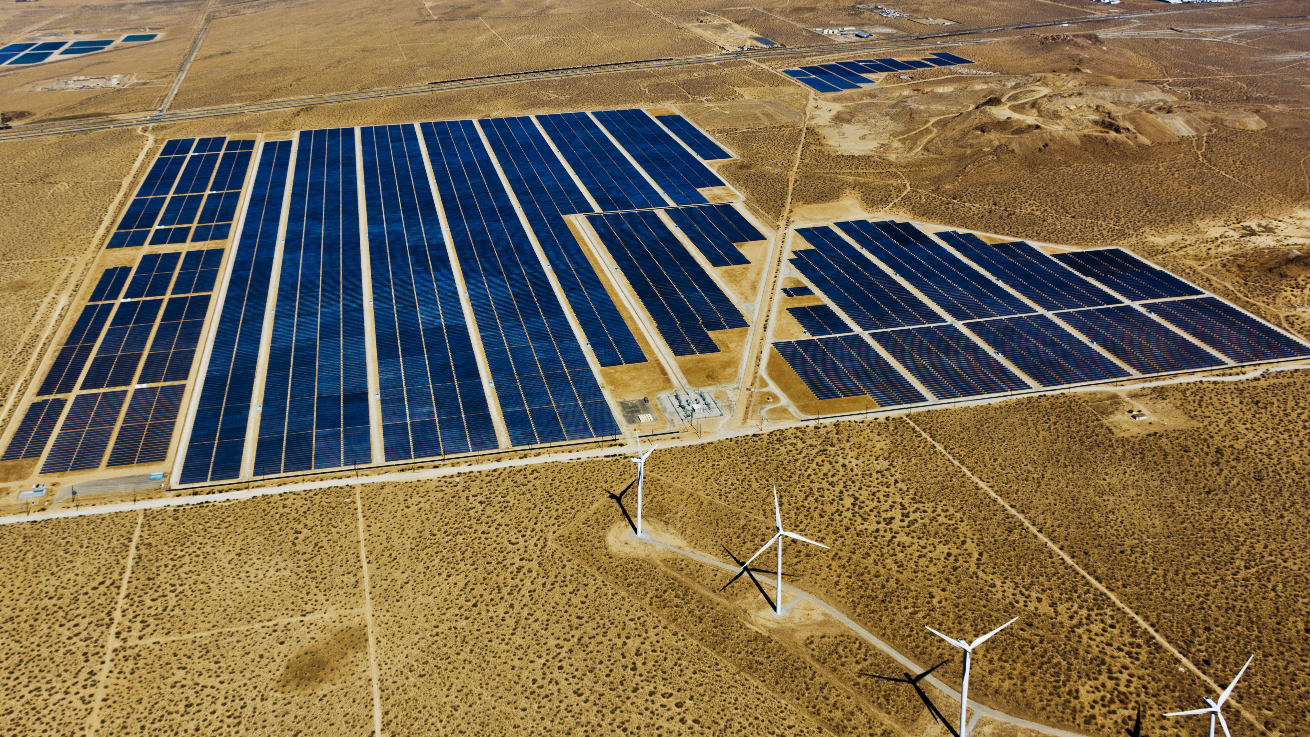 Solar panels and wind turbines in a desert area.