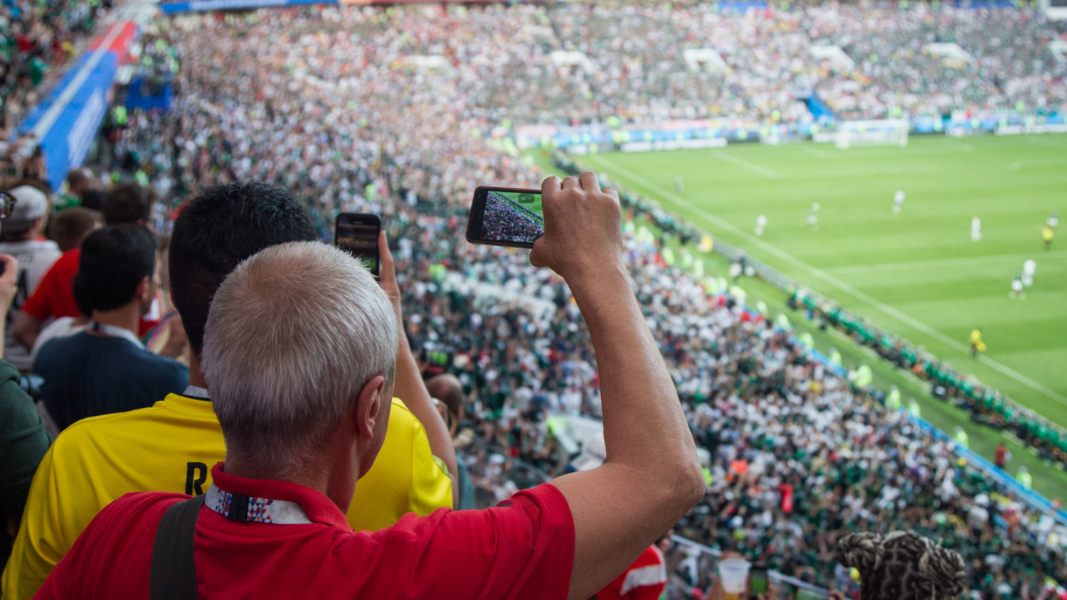 Man at fooball game recording on his smartphone