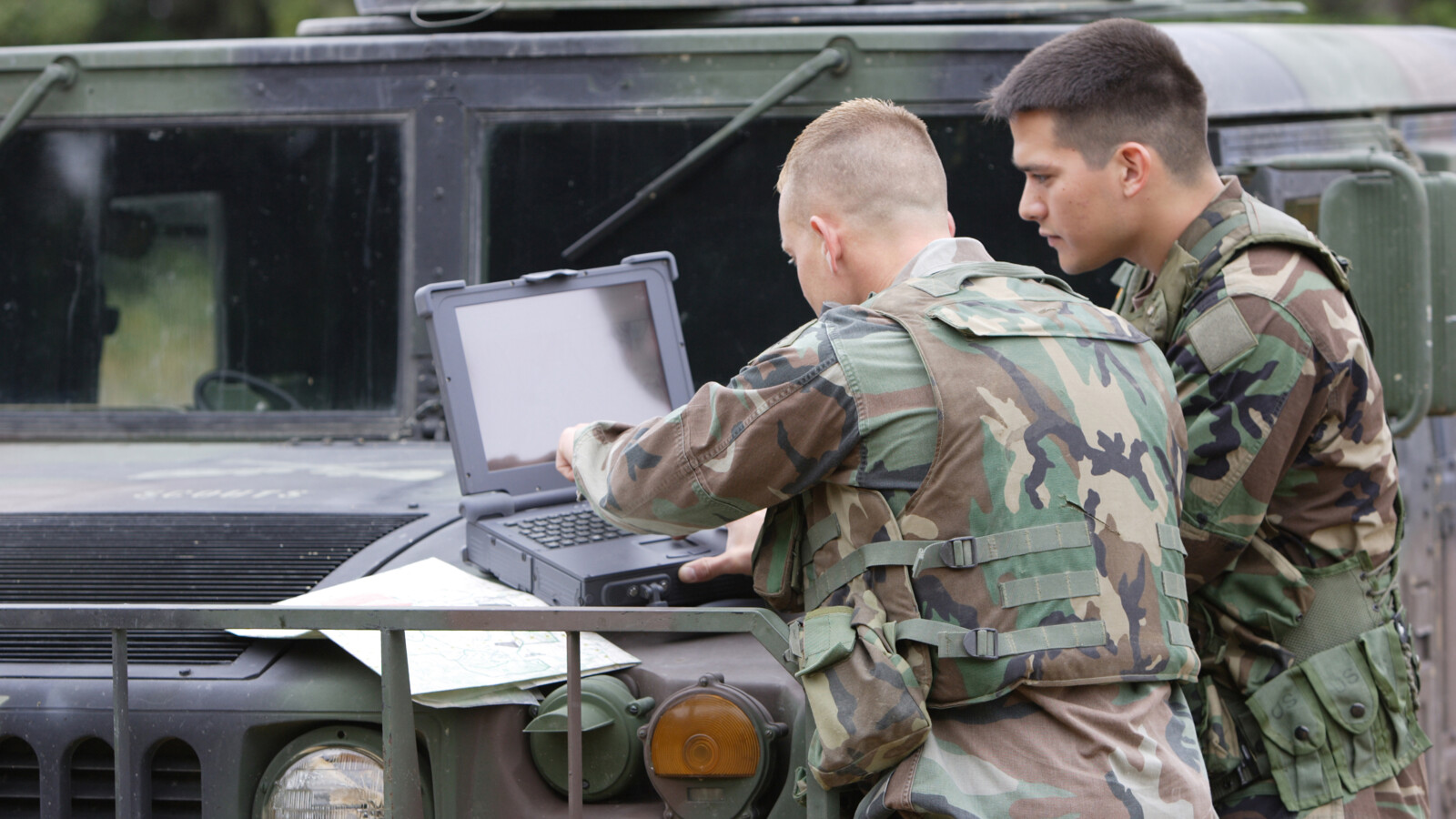 Persons in military clothes using a laptop.