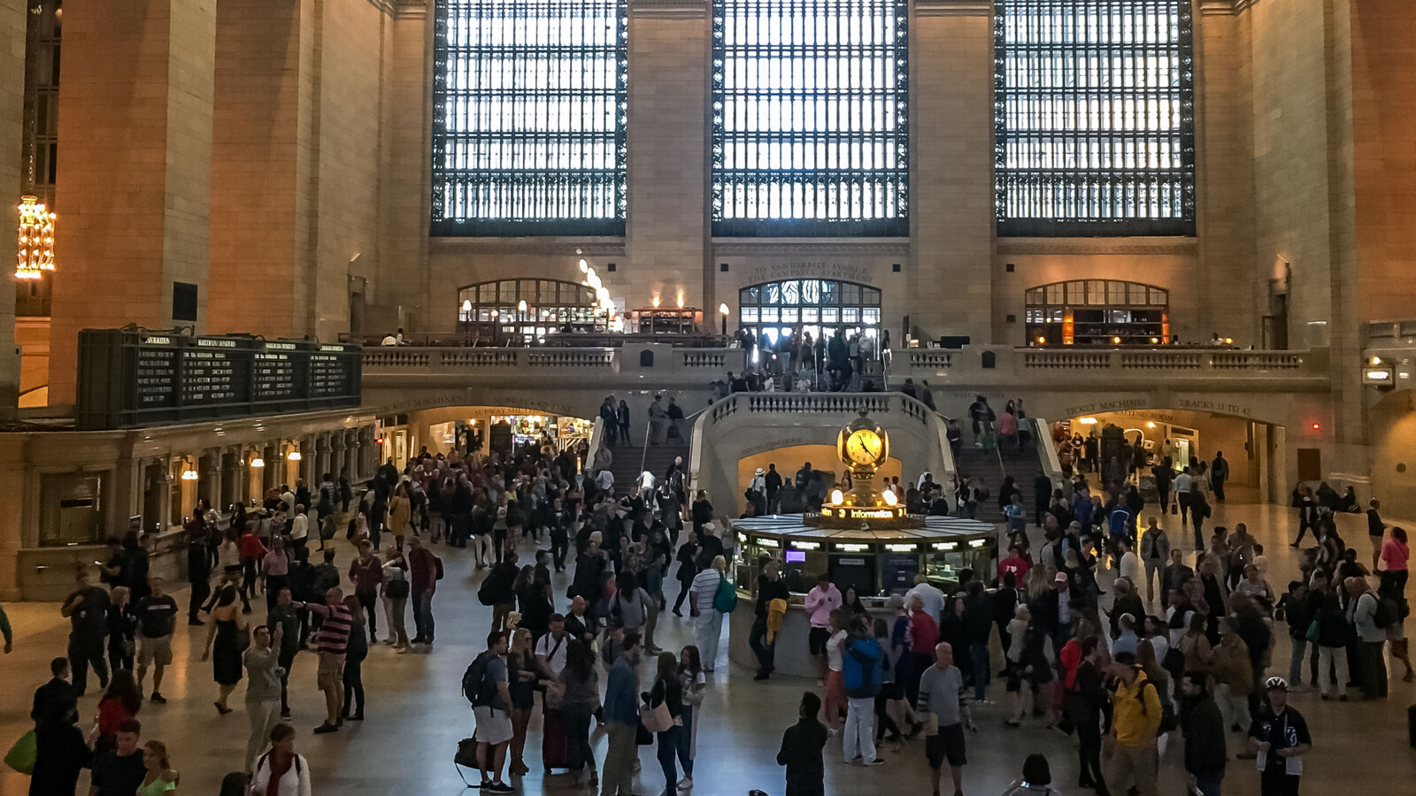 Crowded Grand Central Terminal with iconic clock and windows.