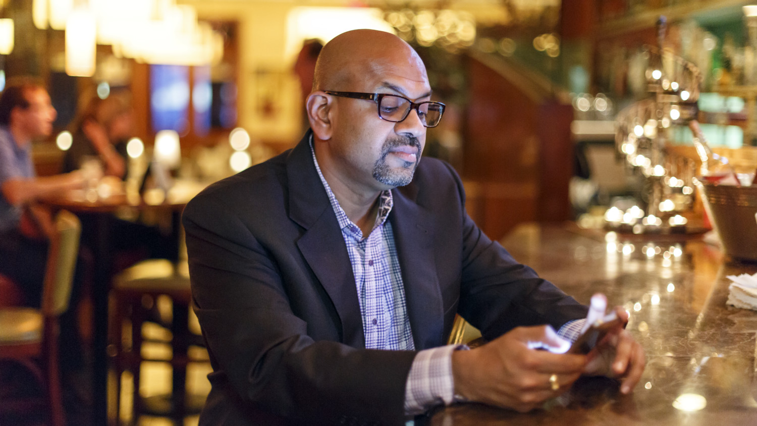Man in a suit looking at a smartphone at a restaurant bar