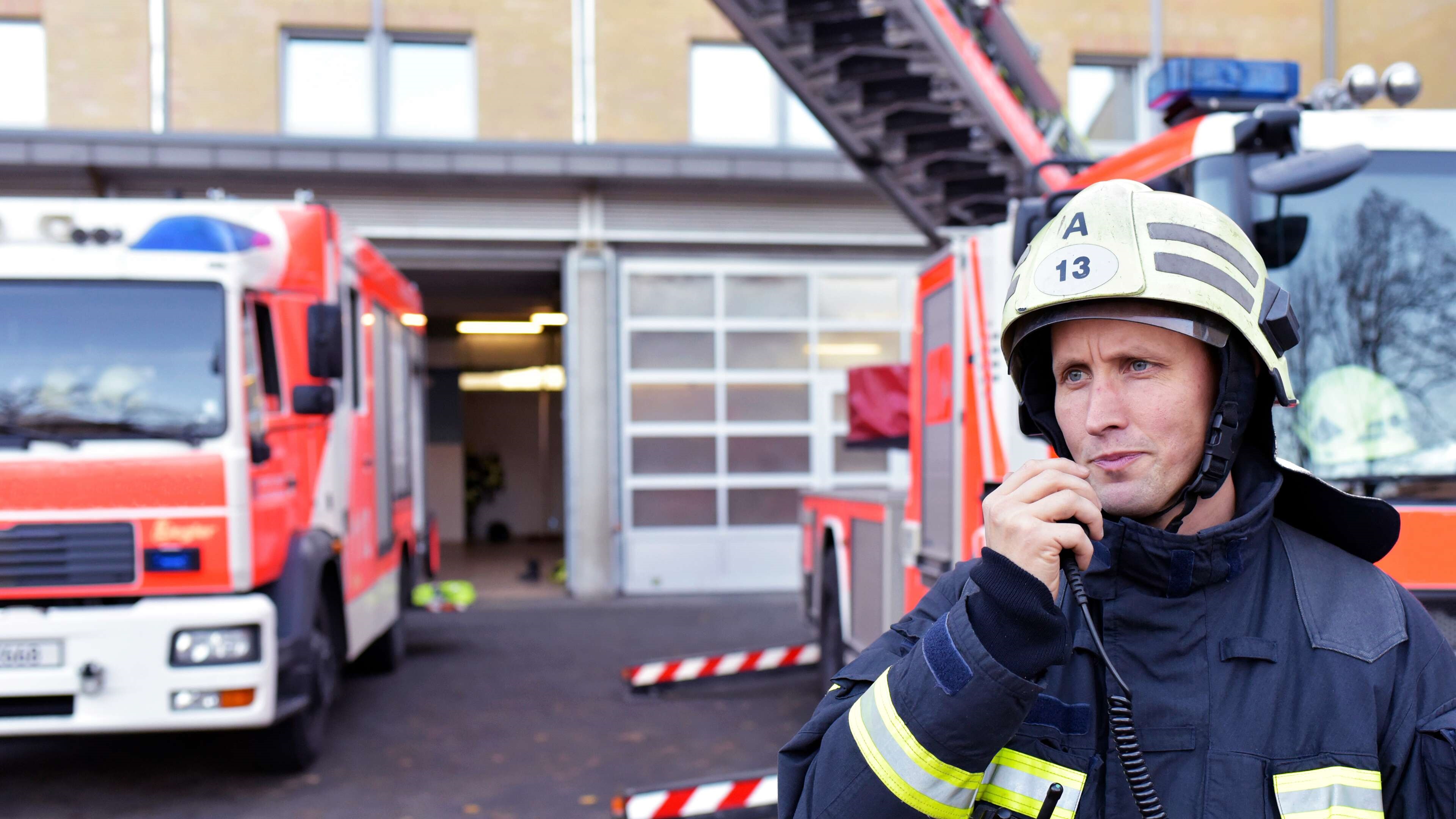 Firefighter standing on yard using walkie talkie.