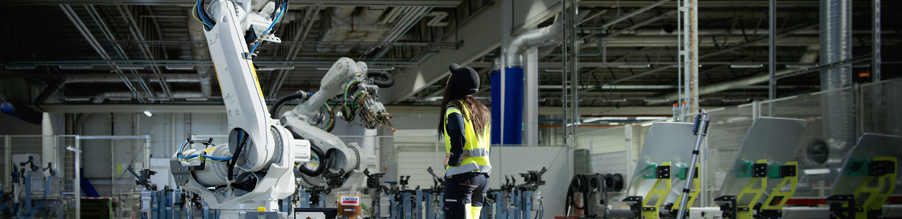 Woman standing in front of a big factory robot. Collaboration ABB Ericsson.