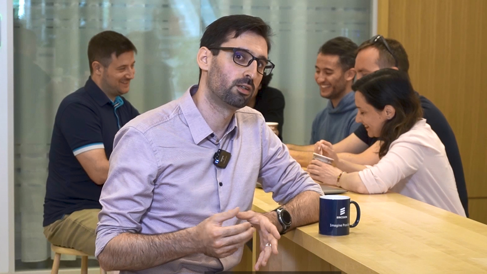 Barnabas Csik sitting in the cafeteria with colleagues in the background