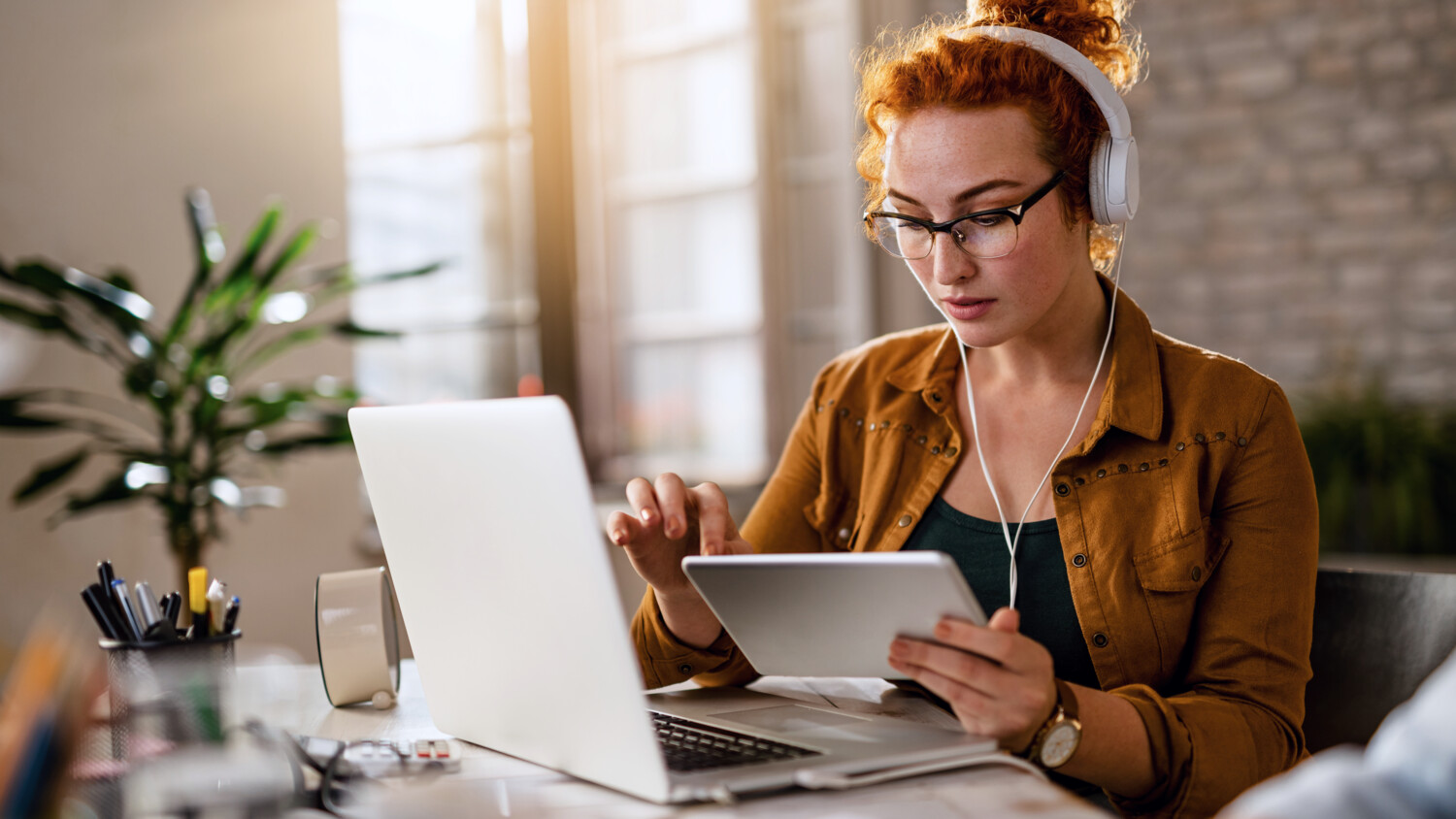 Woman working with digital tablet and wearing headphones