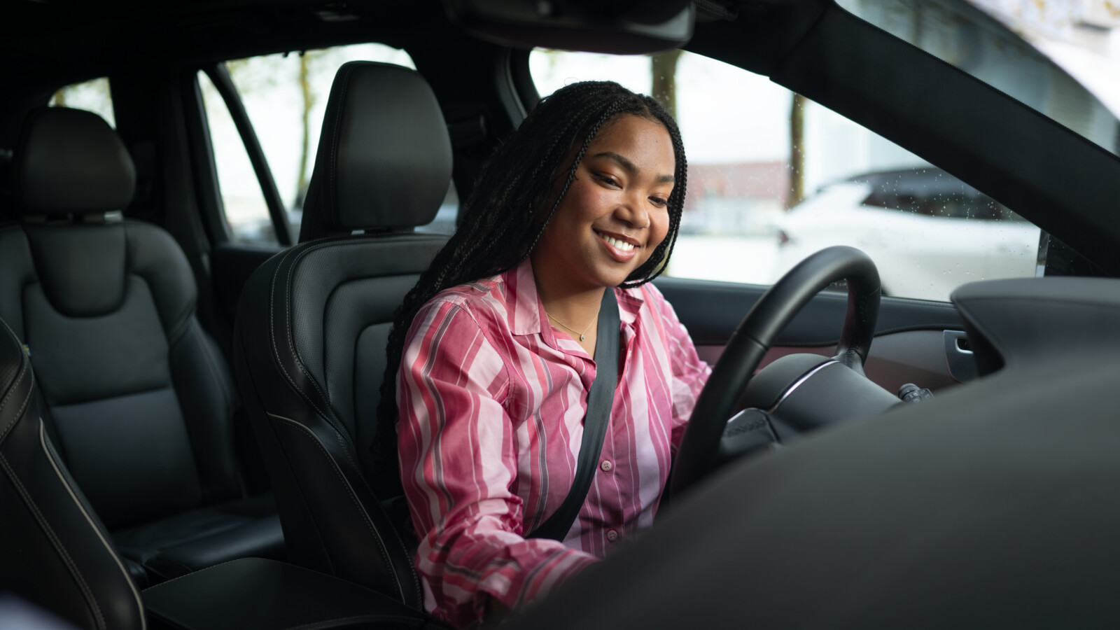Woman is sitting behind the steering wheel in an autonomous vehicle