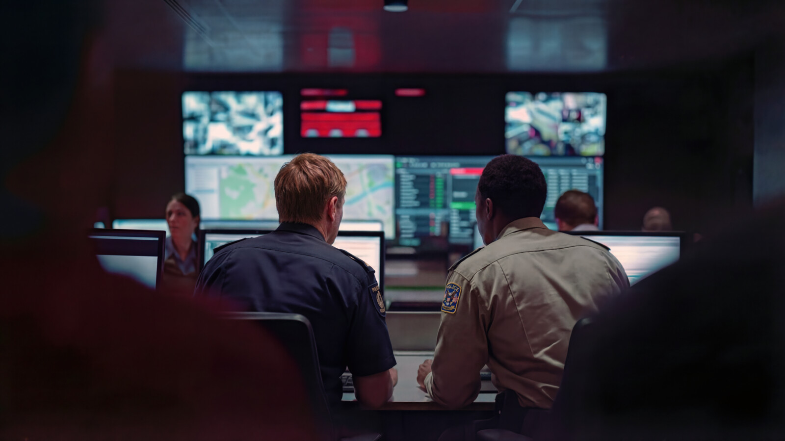 Two people monitoring on multiple screens