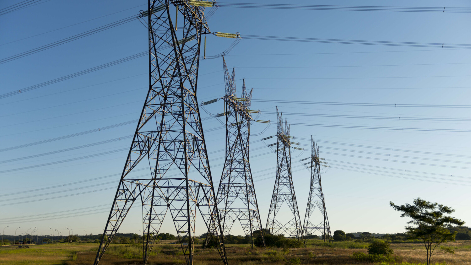 High-voltage towers lined up under a clear blue sky.