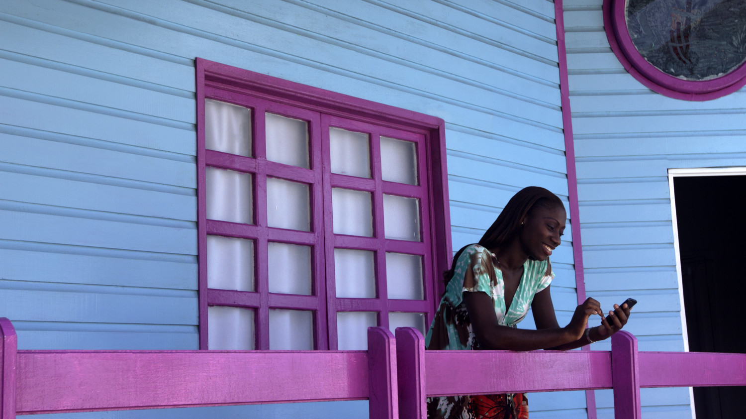 Woman on mobile phone in front of a colorful house.