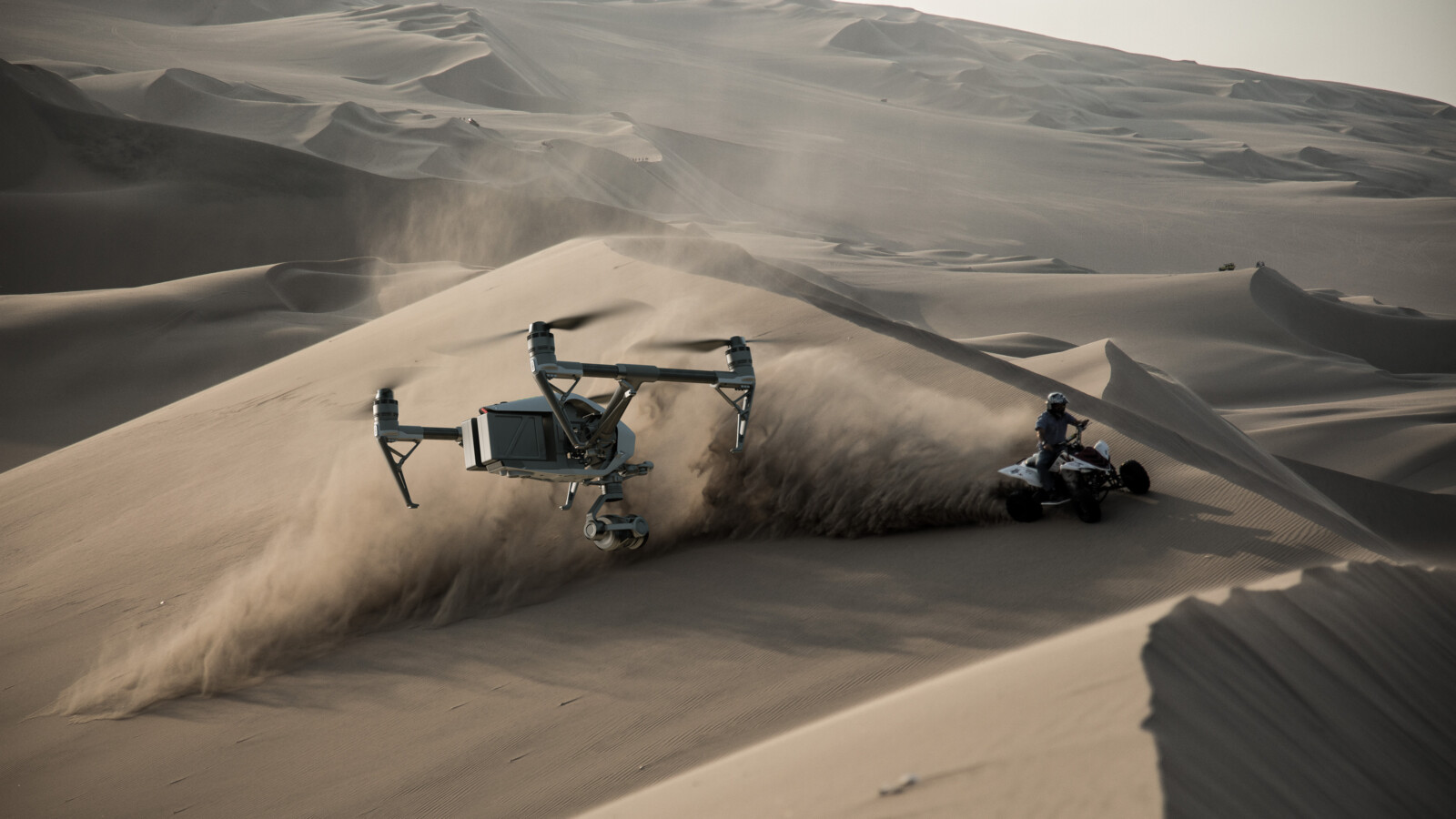 無人機和全地形車高速穿越沙漠沙丘。