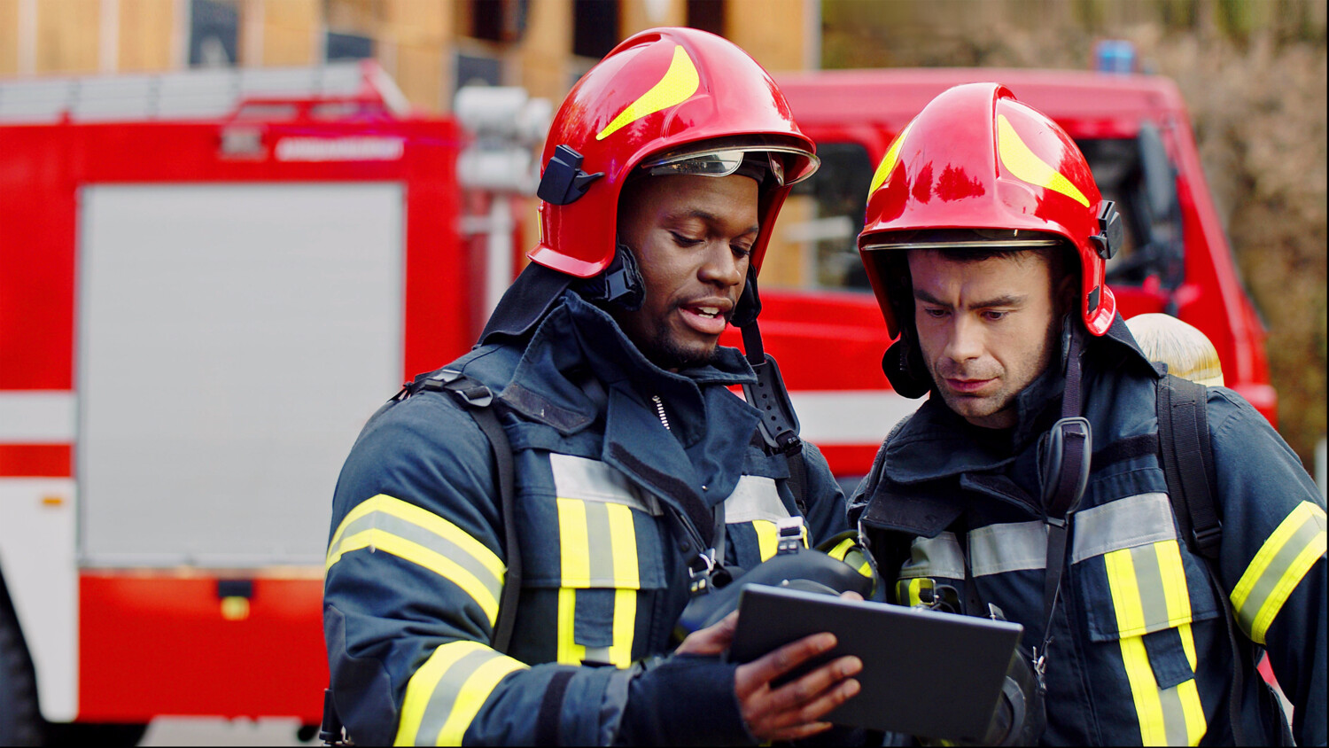 Firemen using tablet to examine building drawings.