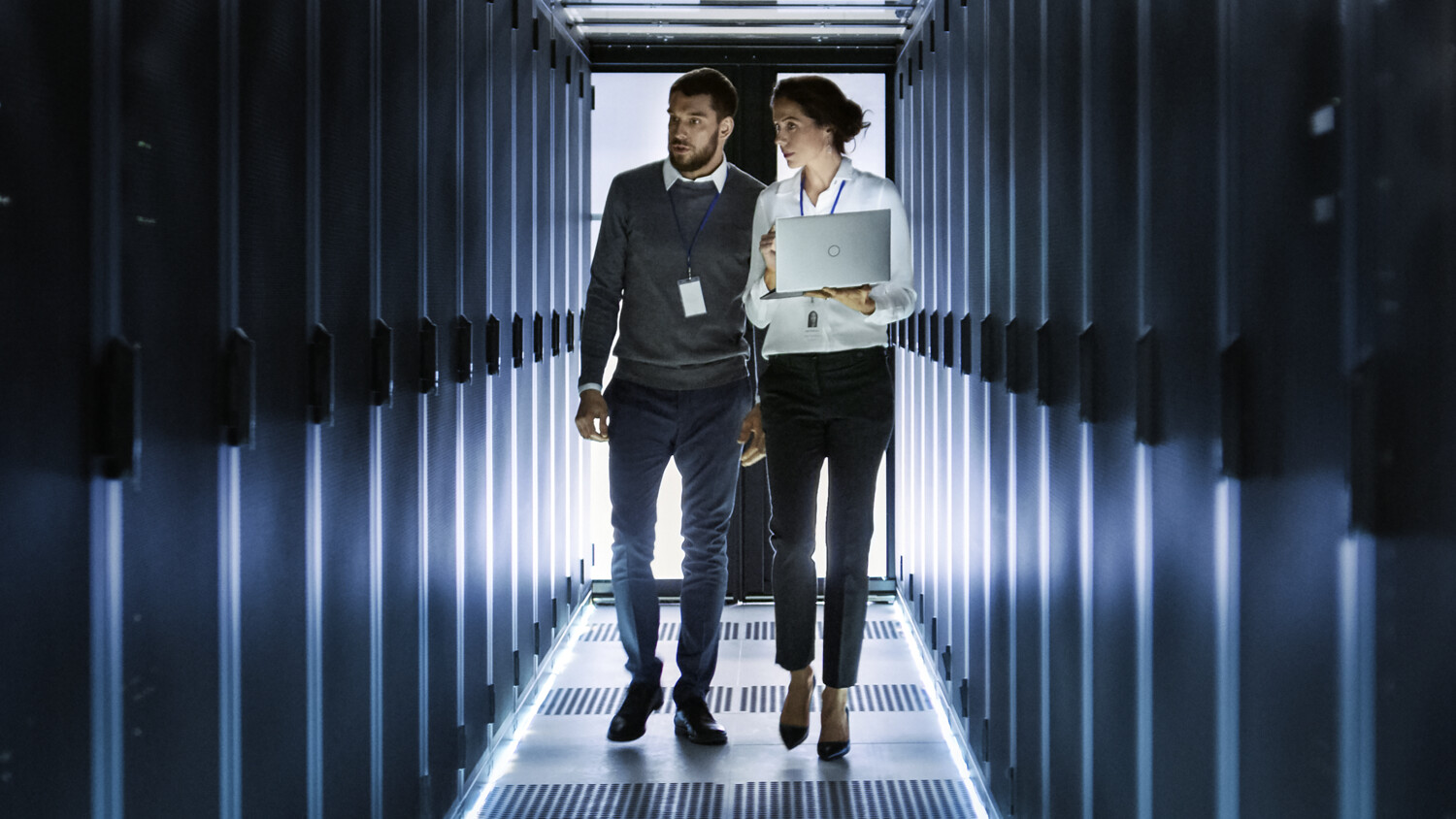 Persons walking in a server room for security.