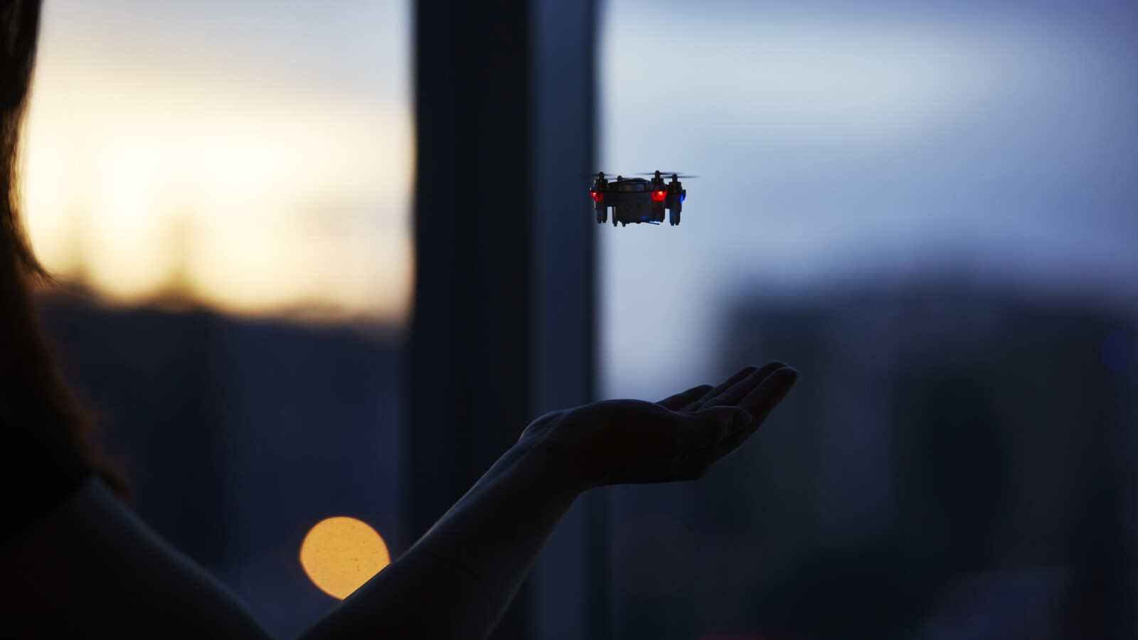 woman holding hand under a small drone. 