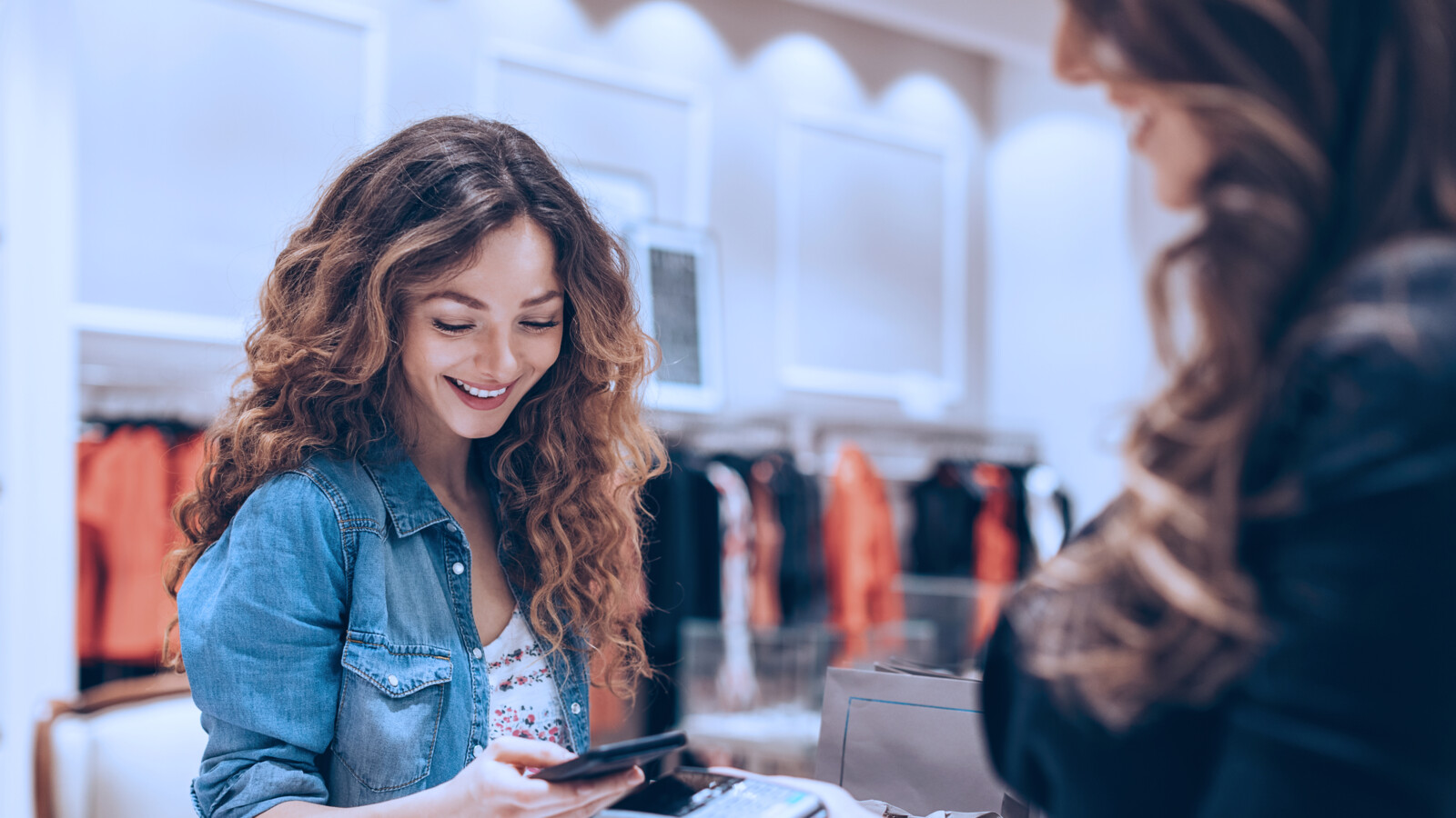 Woman paying with mobile phone in a store.
