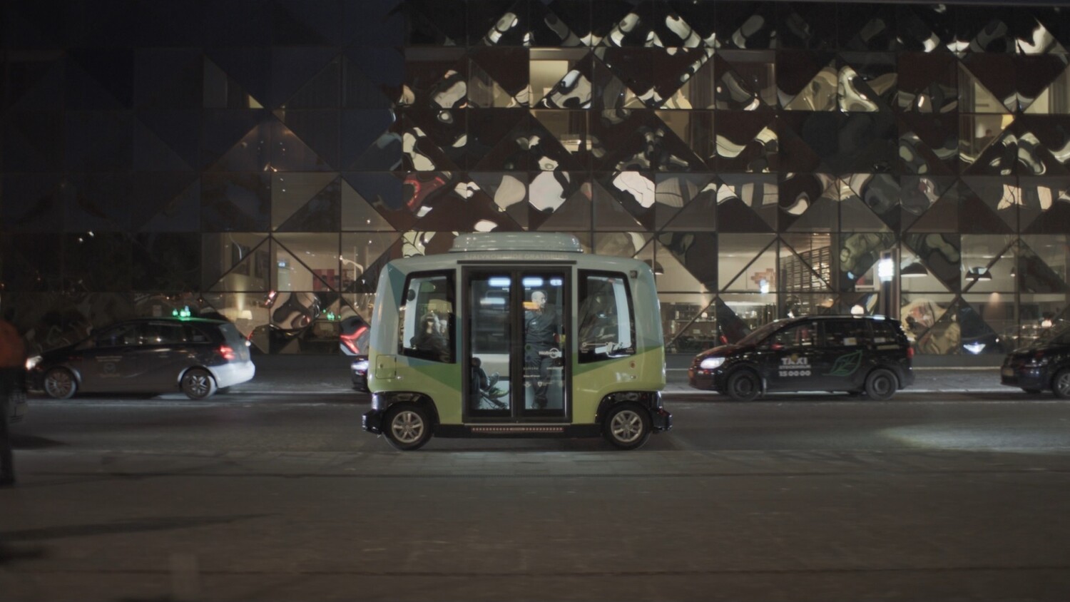 Autonomous shuttle bus on city street at night.
