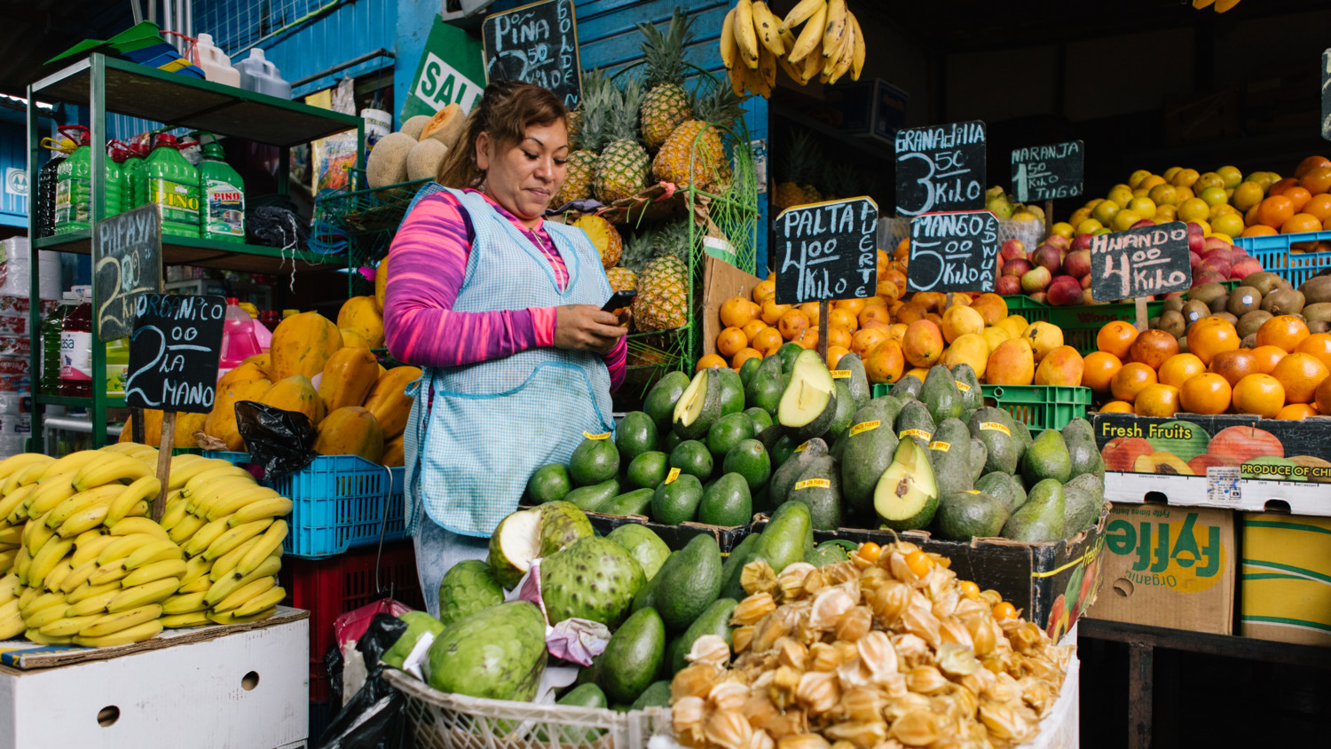 Mujer con su teléfono móvil en el mercado de frutas.