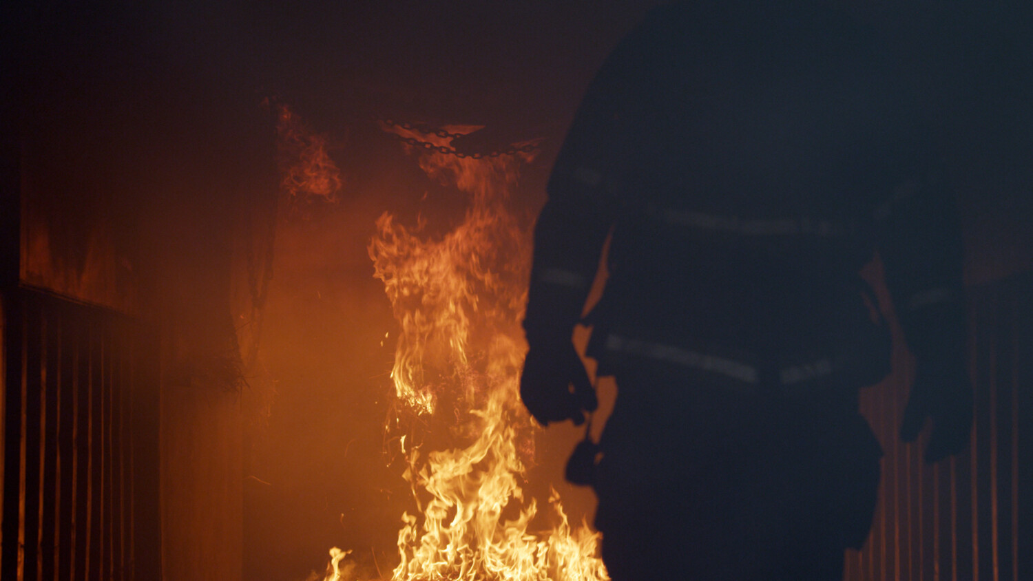 Silhouette of a firefighter and a fire in the background.