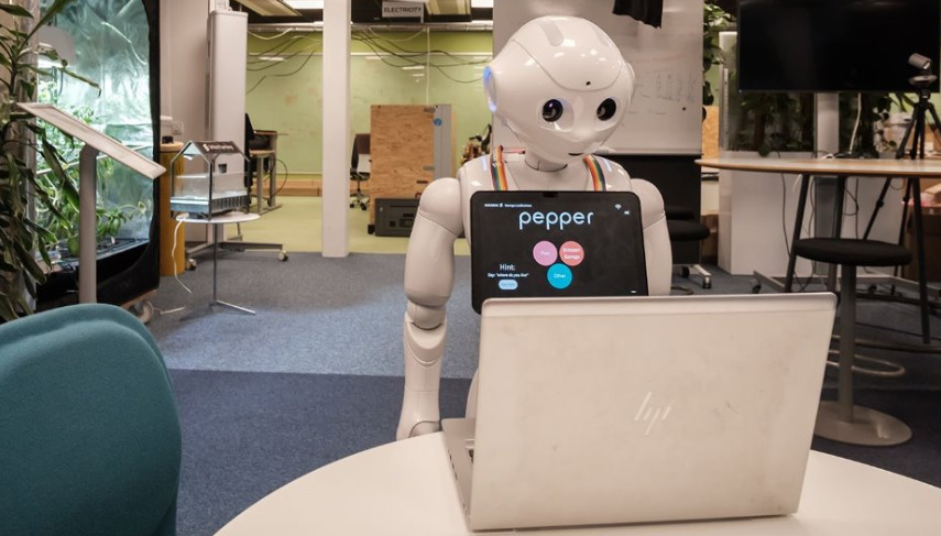Humanoid Robot Pepper working on laptop.