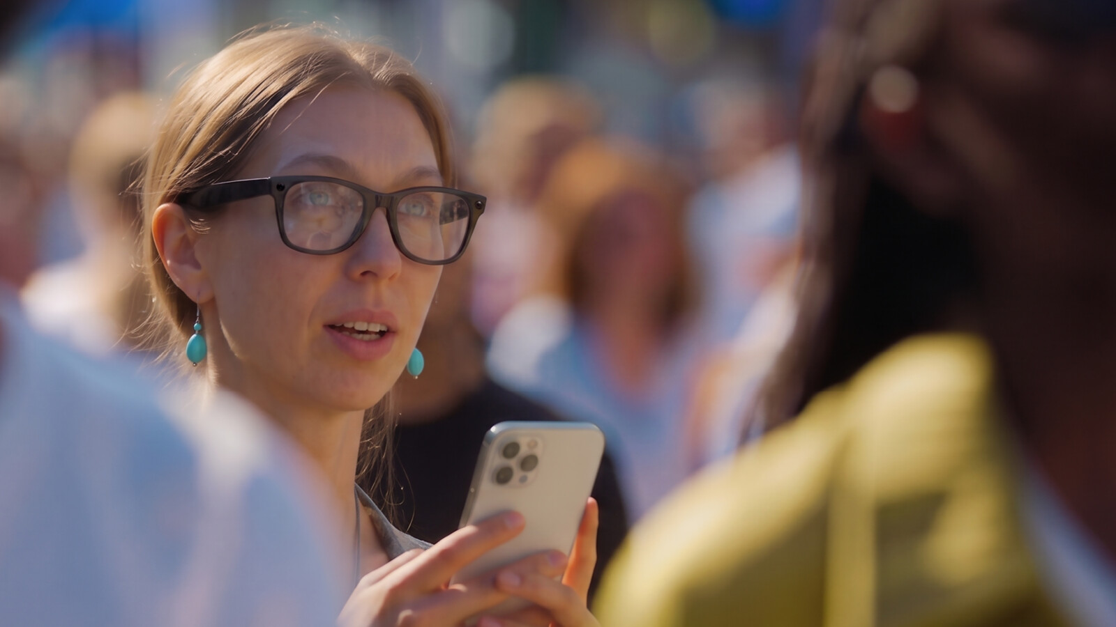 Woman in crowd, holding mobile