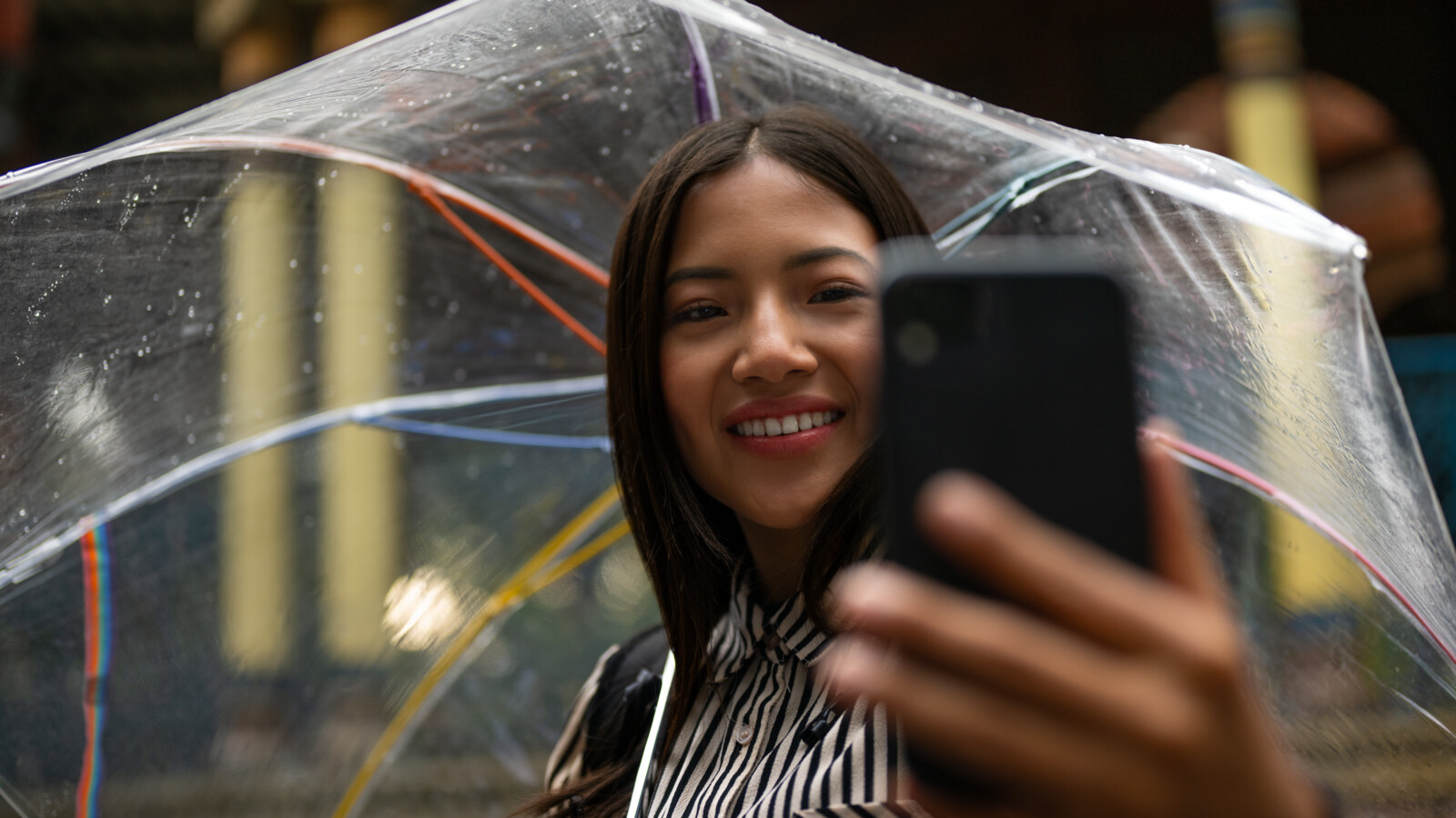 A woman talking a selfie while holding an umbrella