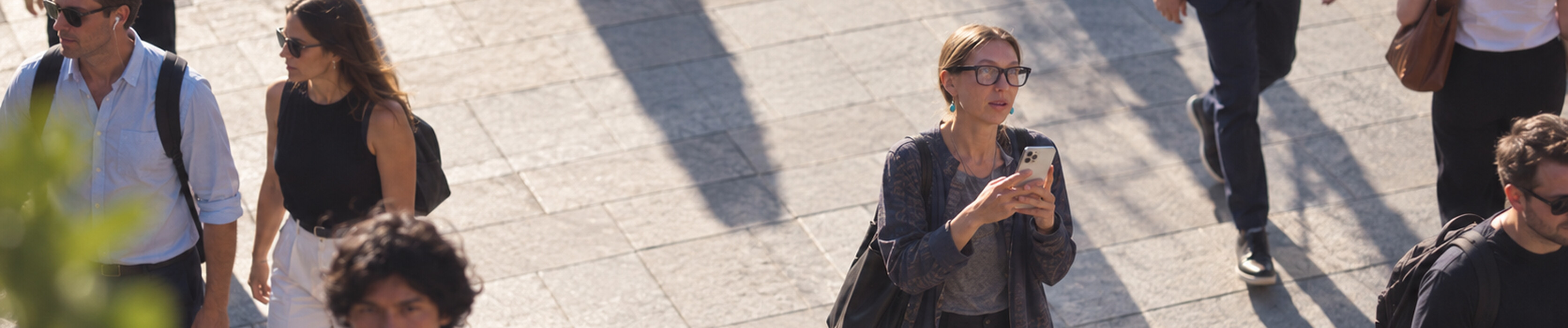 A woman using her phone on a busy city street.