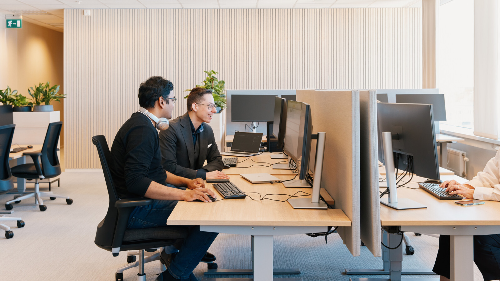 Colleagues discussing in front of computer screens.