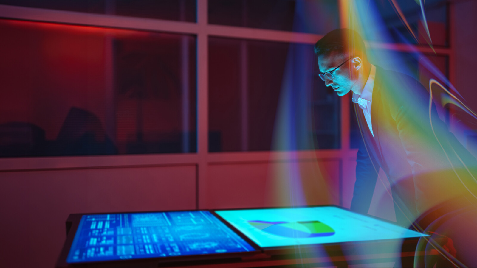 Man looking at graphs on multiple screens.