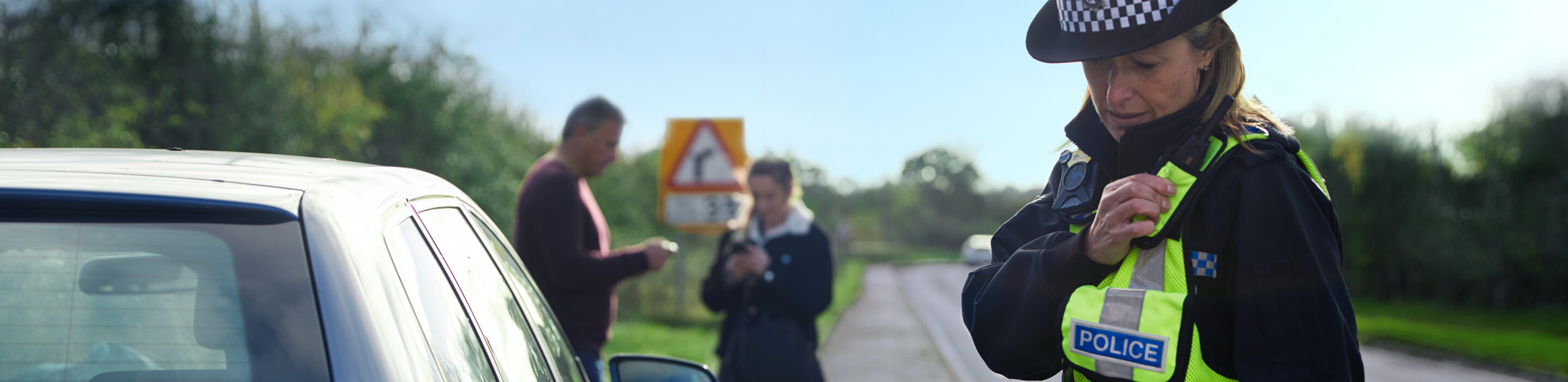 Policewoman using a walkie-talkie by the road side.
