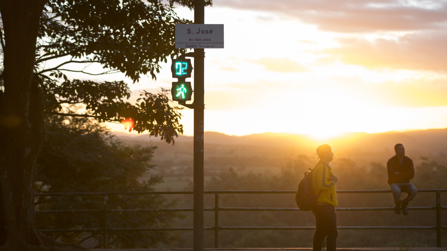 A man wearing running clothes standing next to traffic lights.