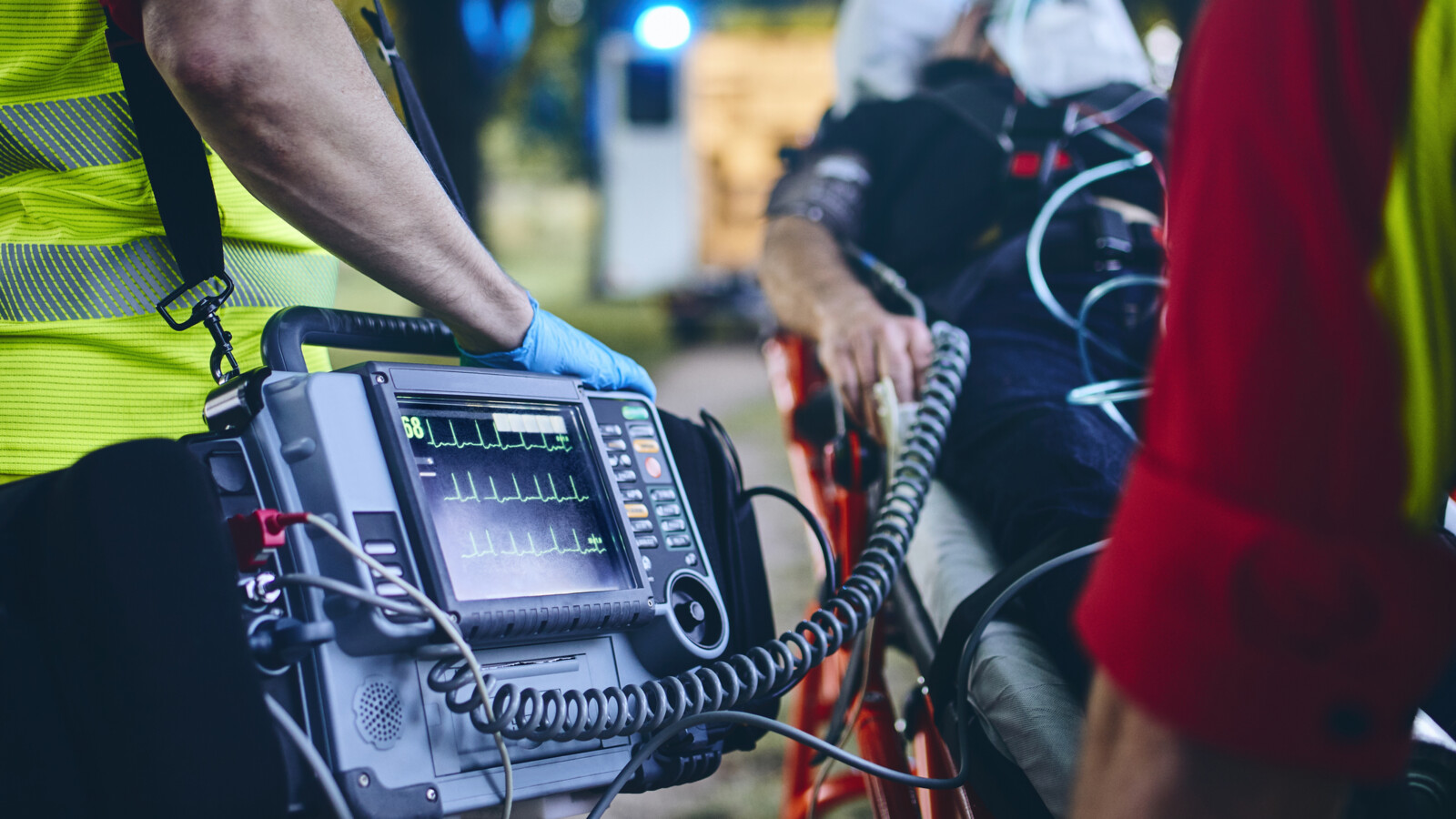 Paramedic using defibrillator on patient outdoors.