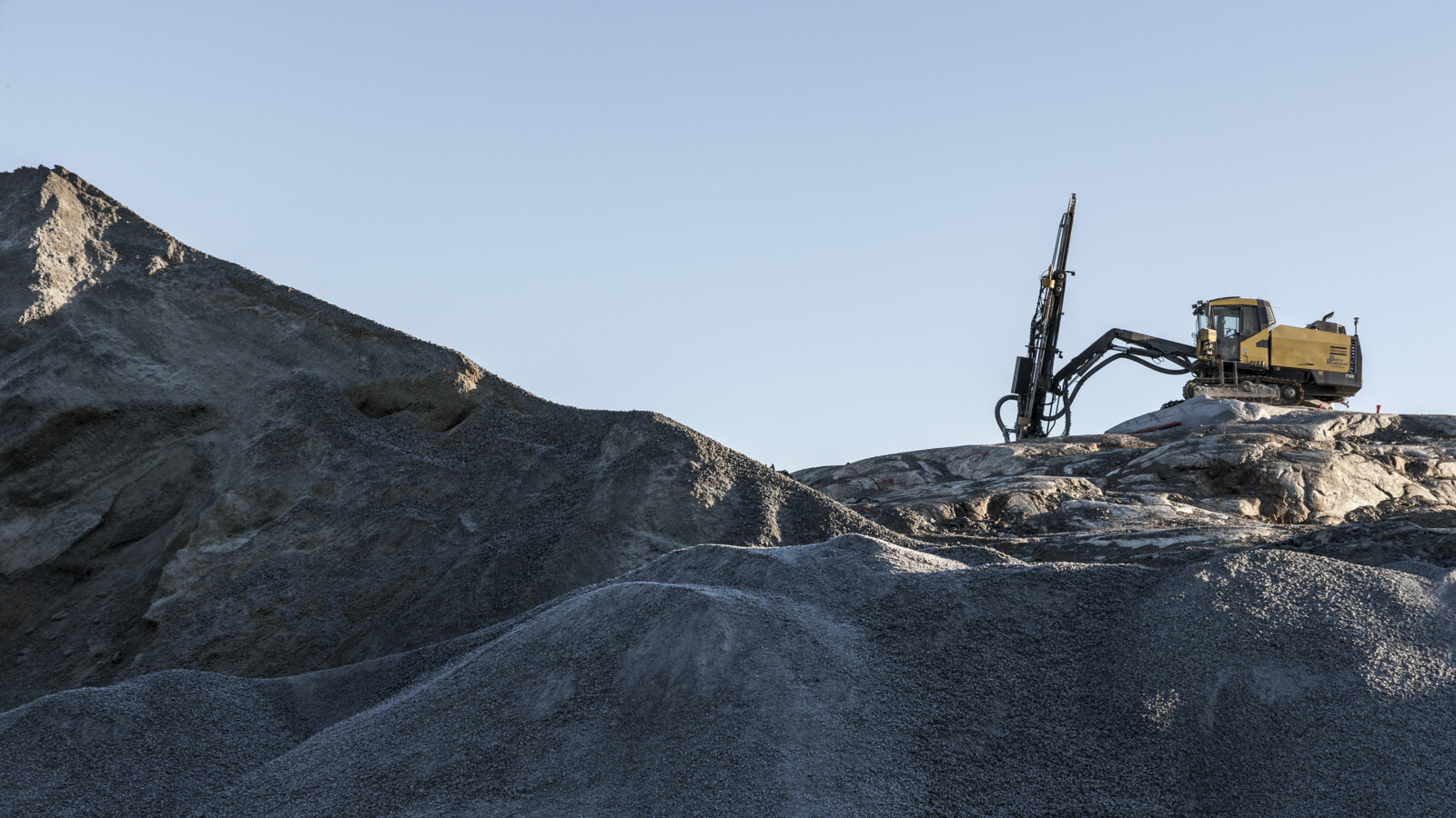 Mining excavator on rocky hill.