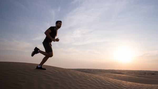 Man running in desert during sunset.