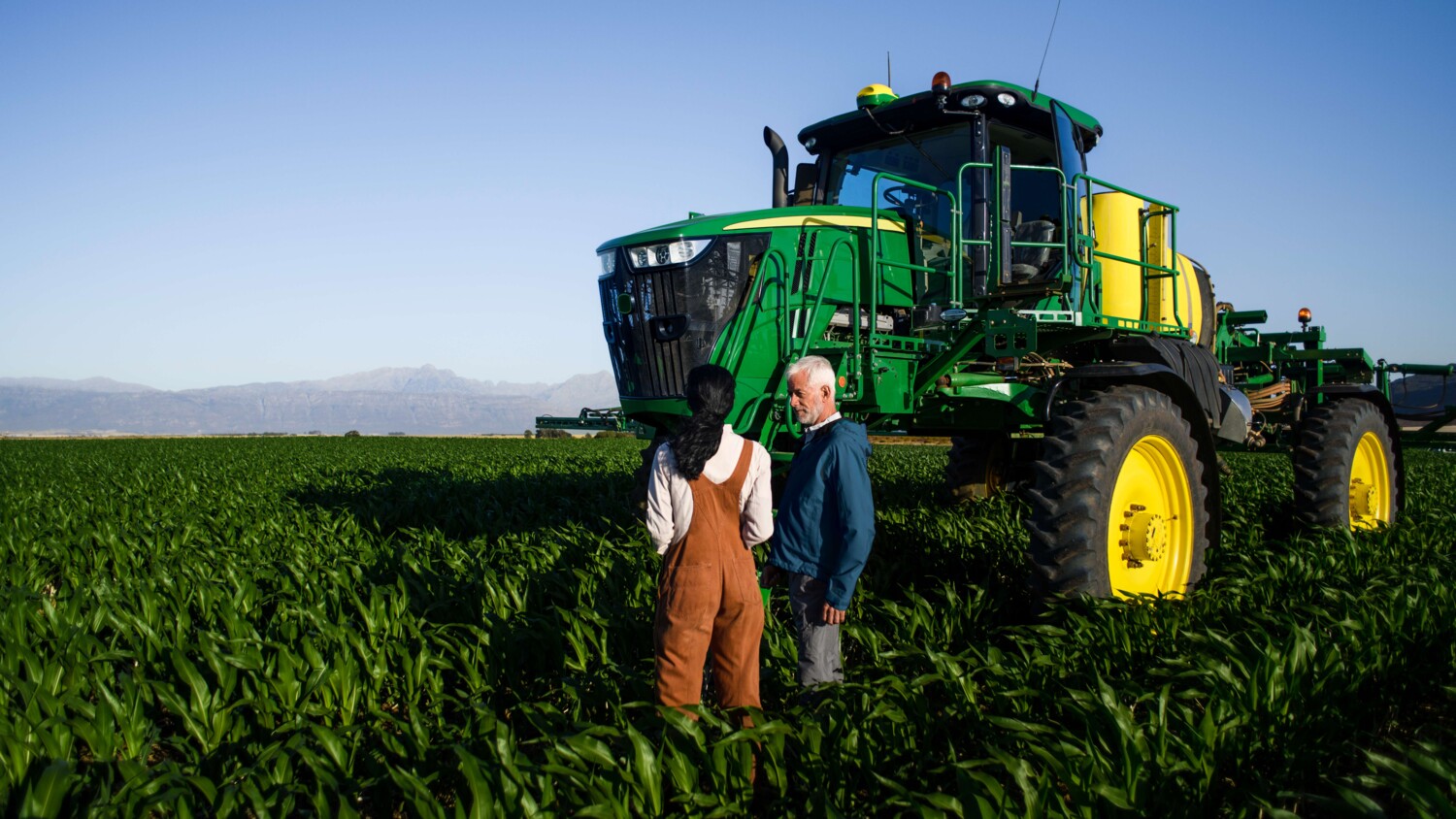 A man and a woman with a connected tractor in a field of crops