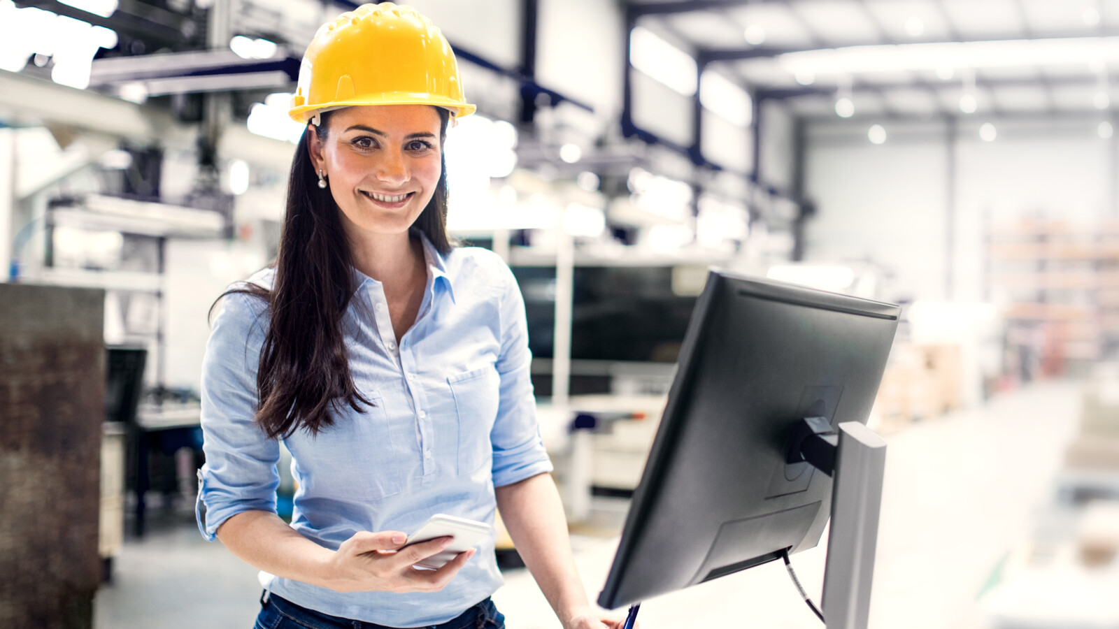 Industrial engineer using smartphone in factory.