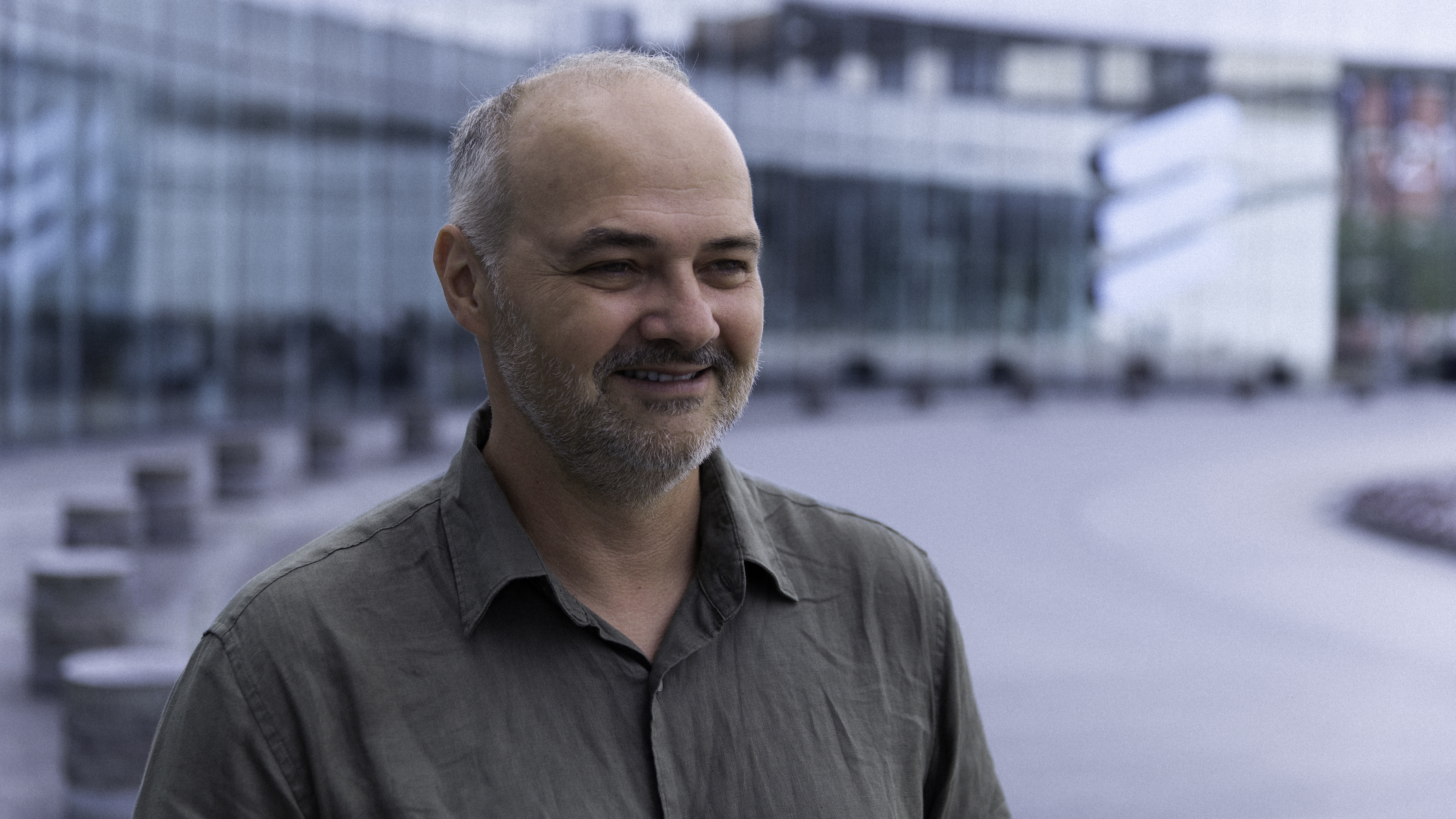 Image of inventor of the year winner David C wearing a dark greenish grey shirt standing in front of Ericsson's headquarters in Stockholm Sweden