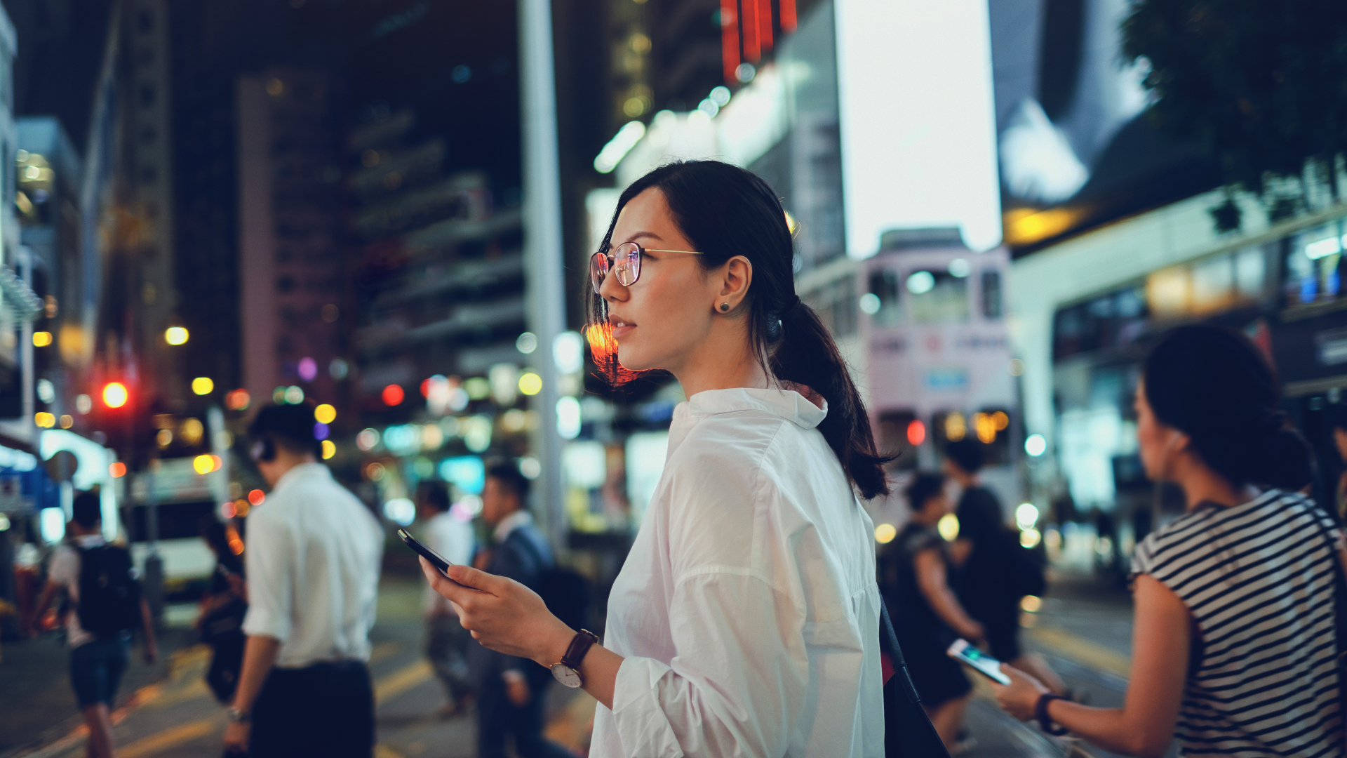 A woman in a city holding a phone.