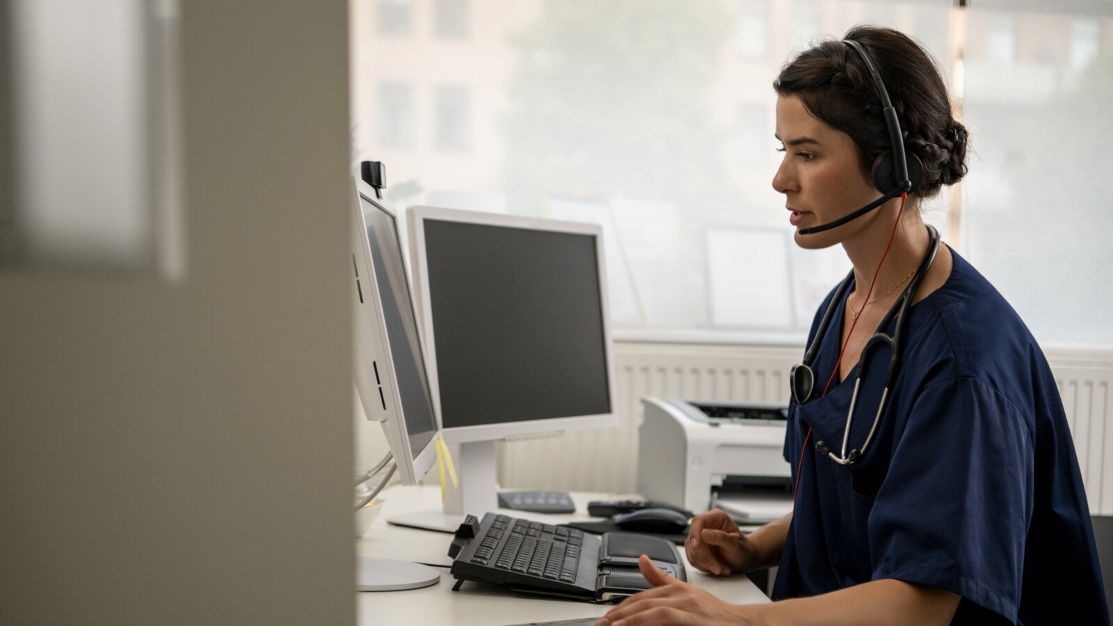 Person with headset in front of computer screens.