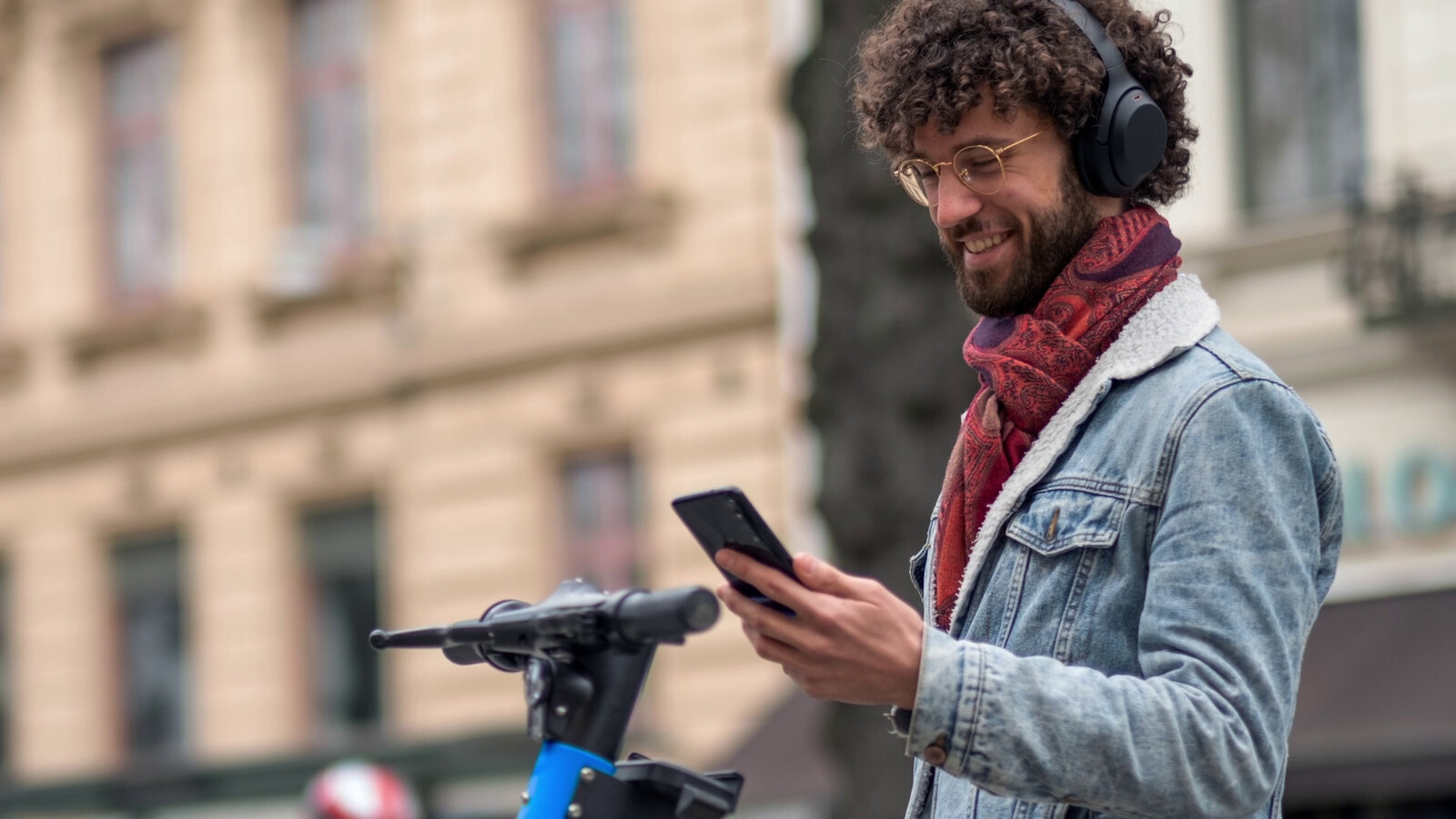 Man with an electric scooter stopping to open mobile phone.