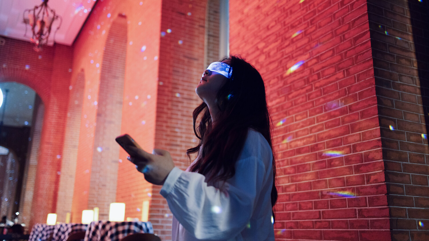 Woman using AR glasses and mobile phone indoors.